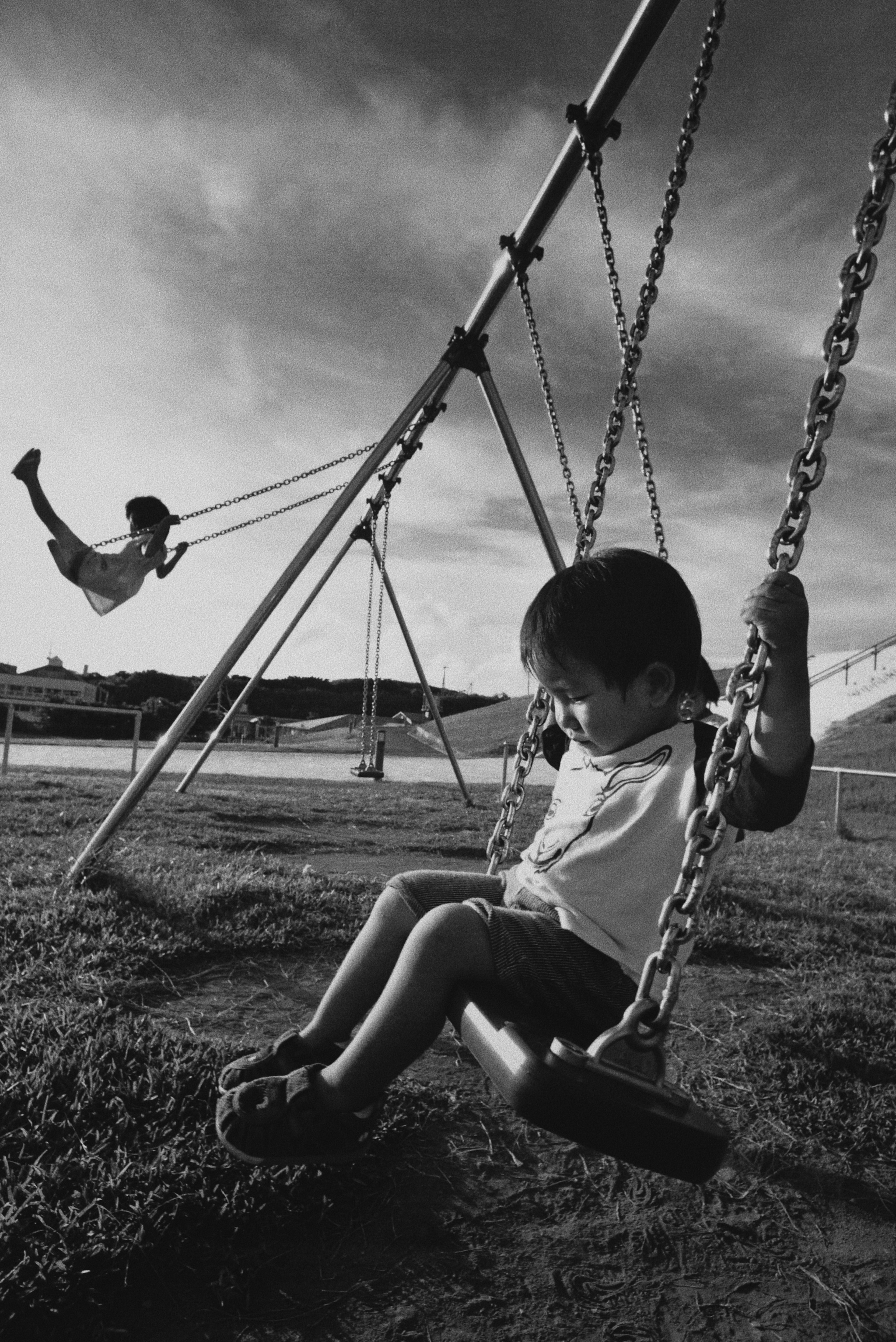 Black and white photo of children playing on swings