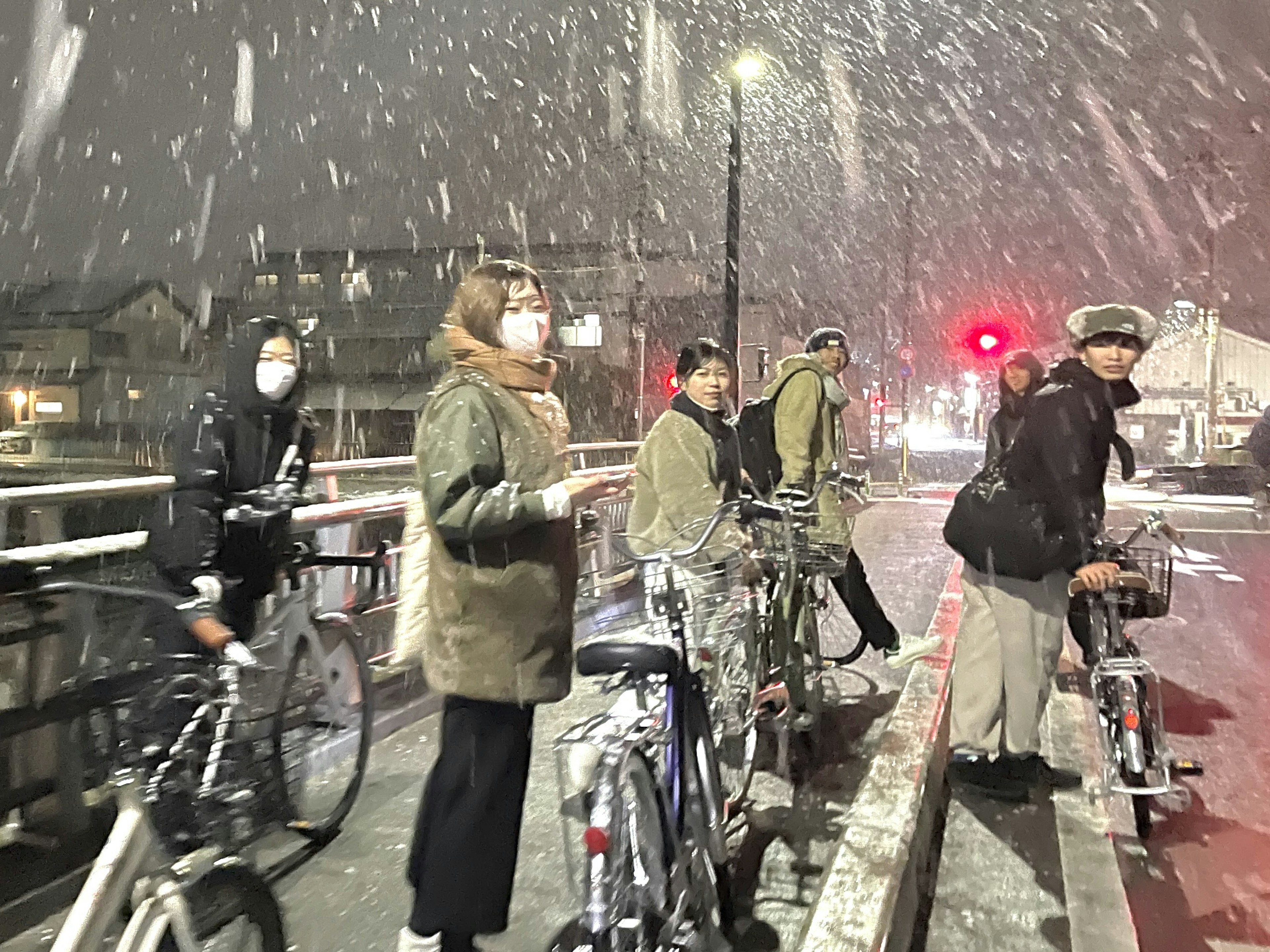 雪の中で自転車に乗る人々のグループが立っている