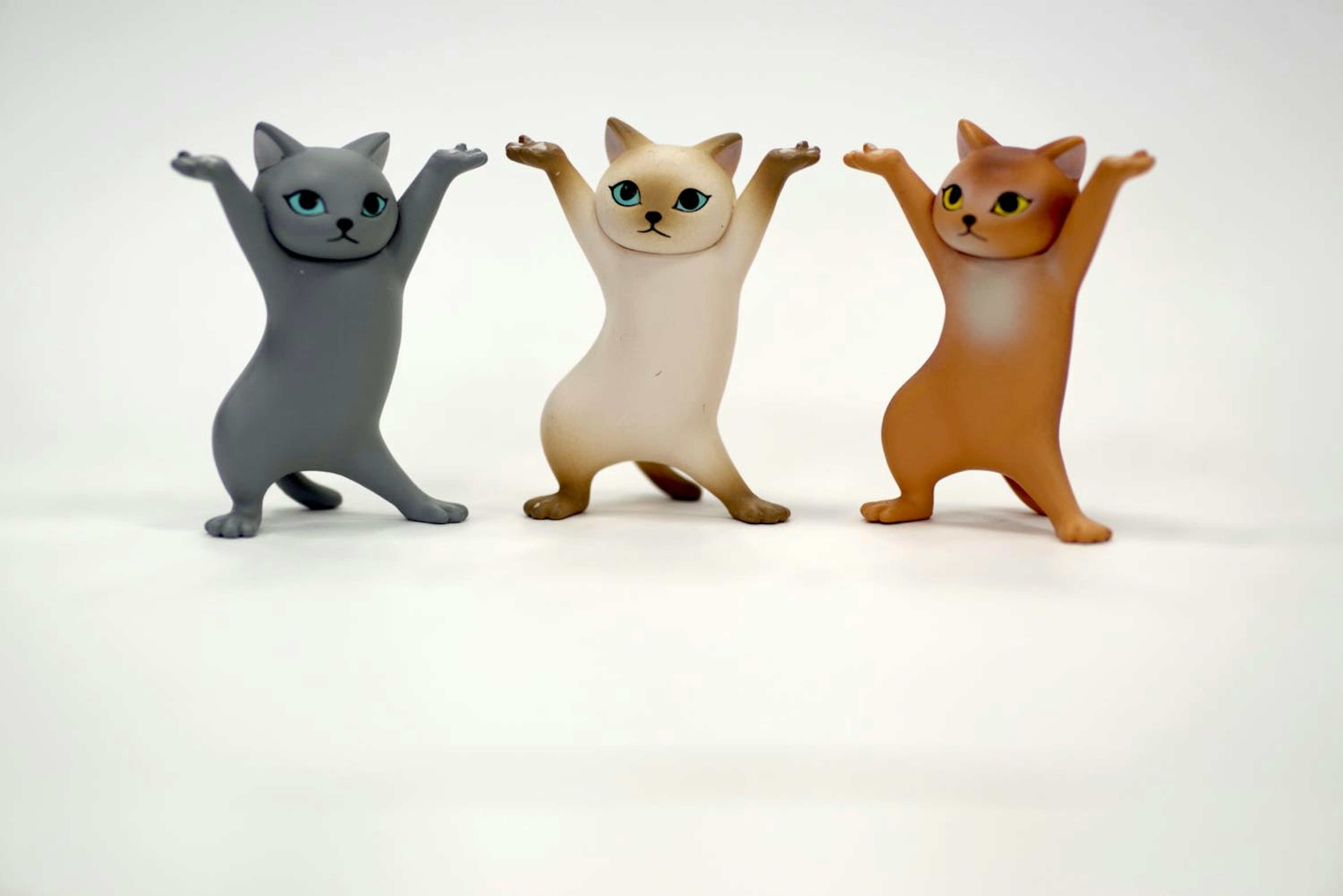 Three cat figurines standing joyfully