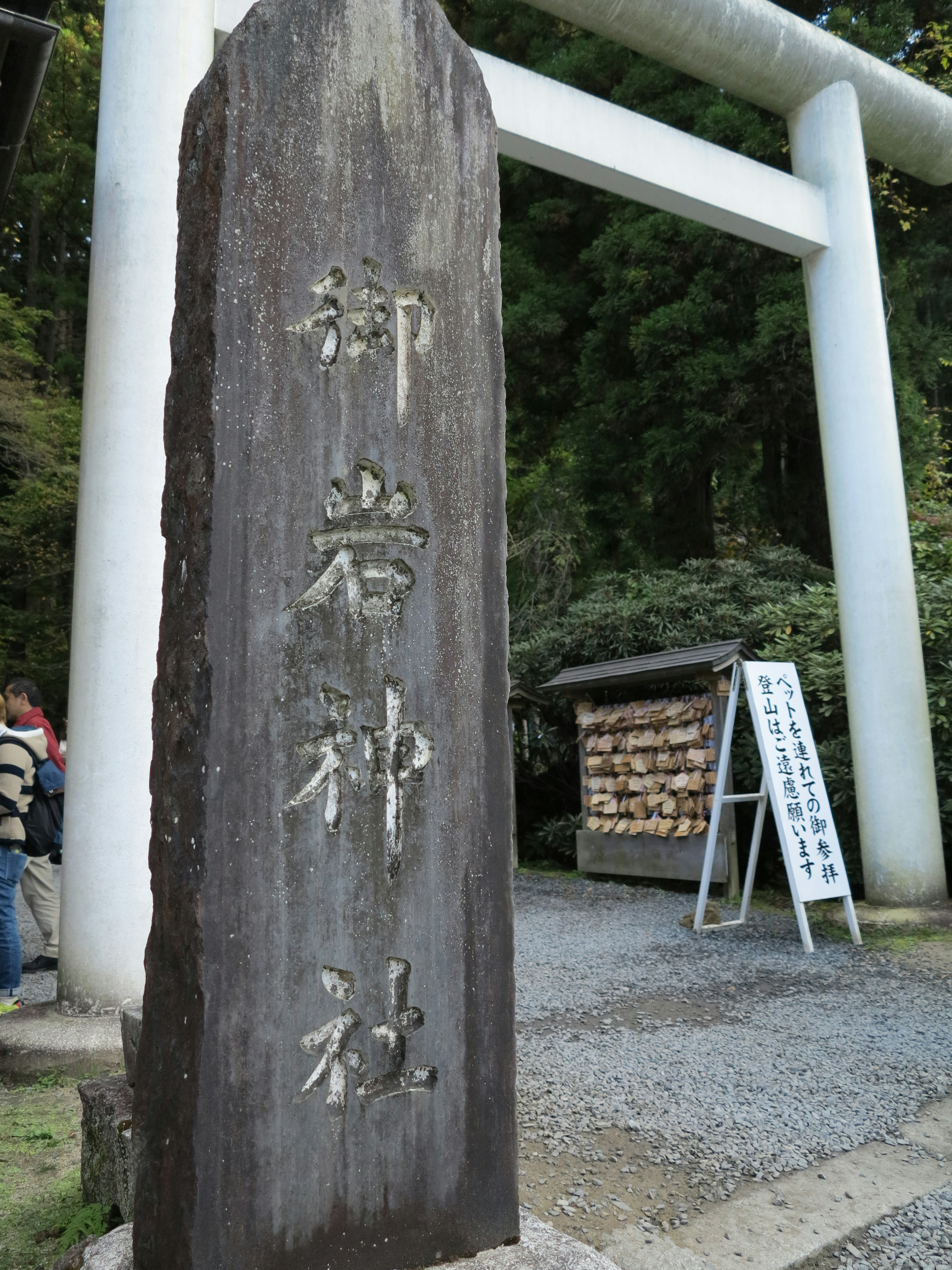 岩神社的石碑，背景有鳥居和告示牌