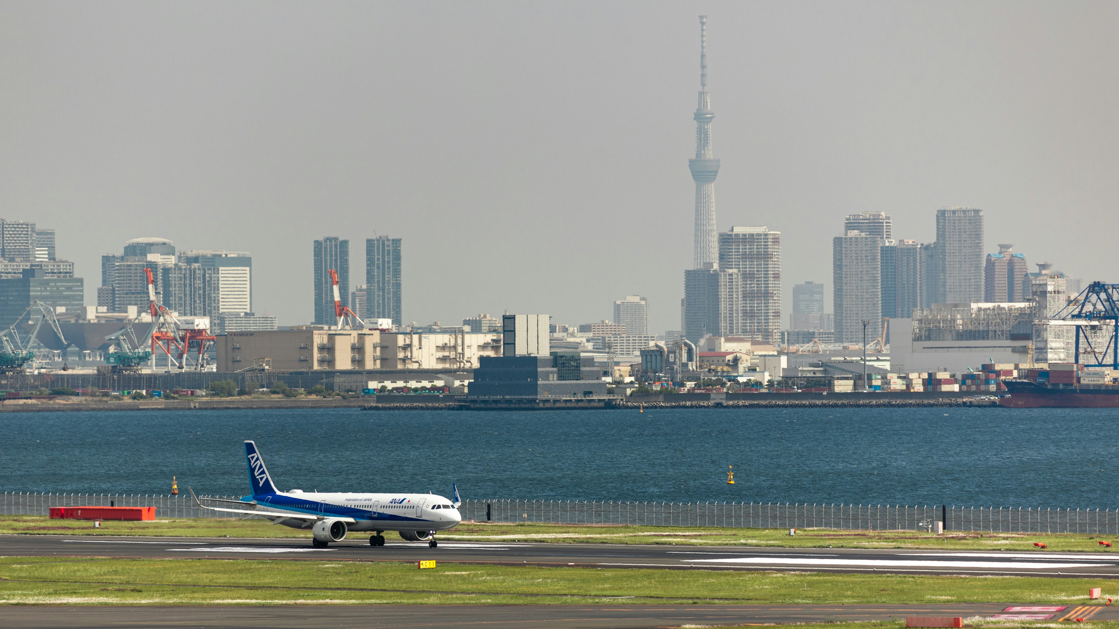 Máy bay đang lăn trên đường băng với Tokyo Skytree ở phía sau