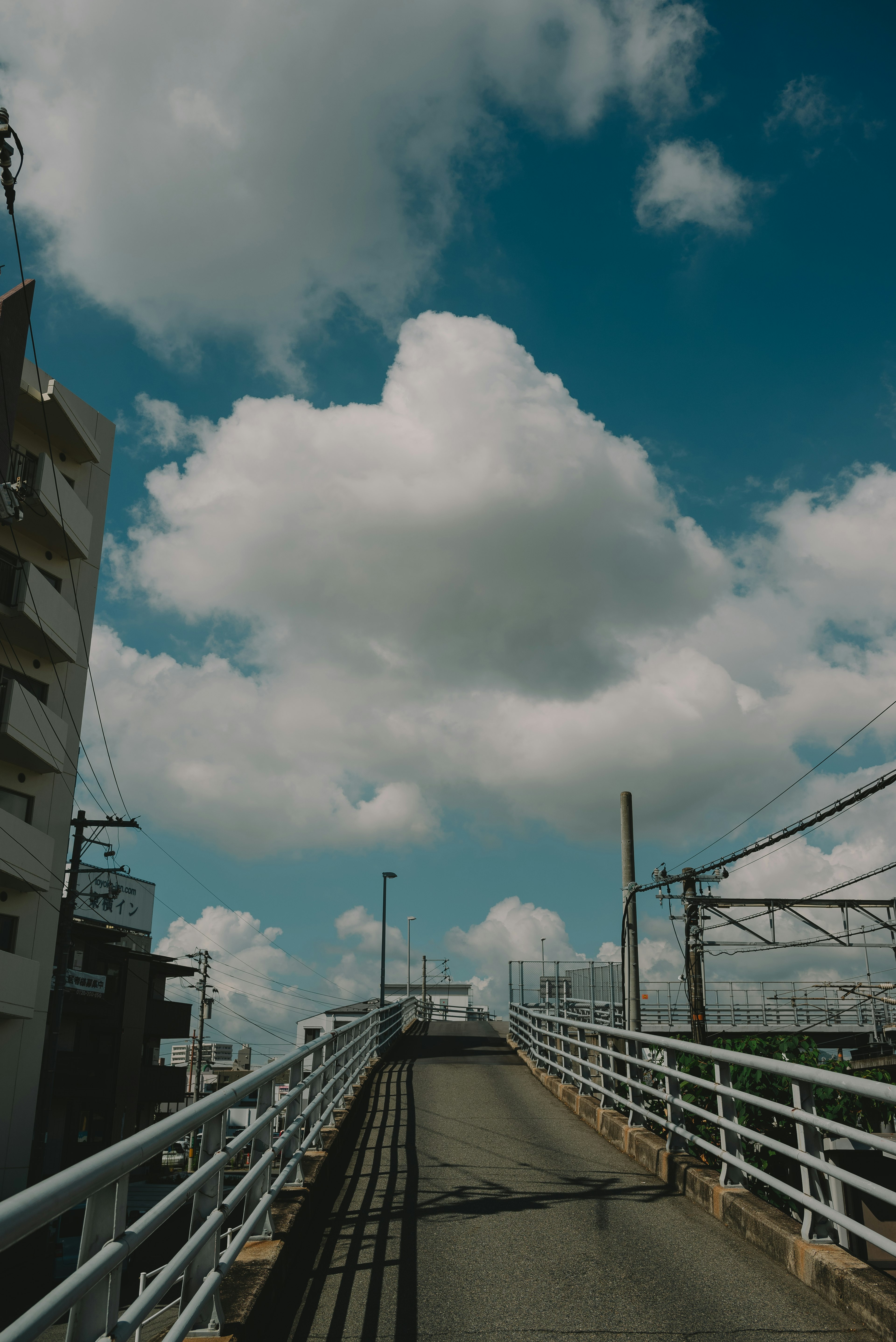 สะพานคนเดินที่นำไปสู่นภากาศพร้อมเมฆขาวและพื้นหลังสีน้ำเงิน