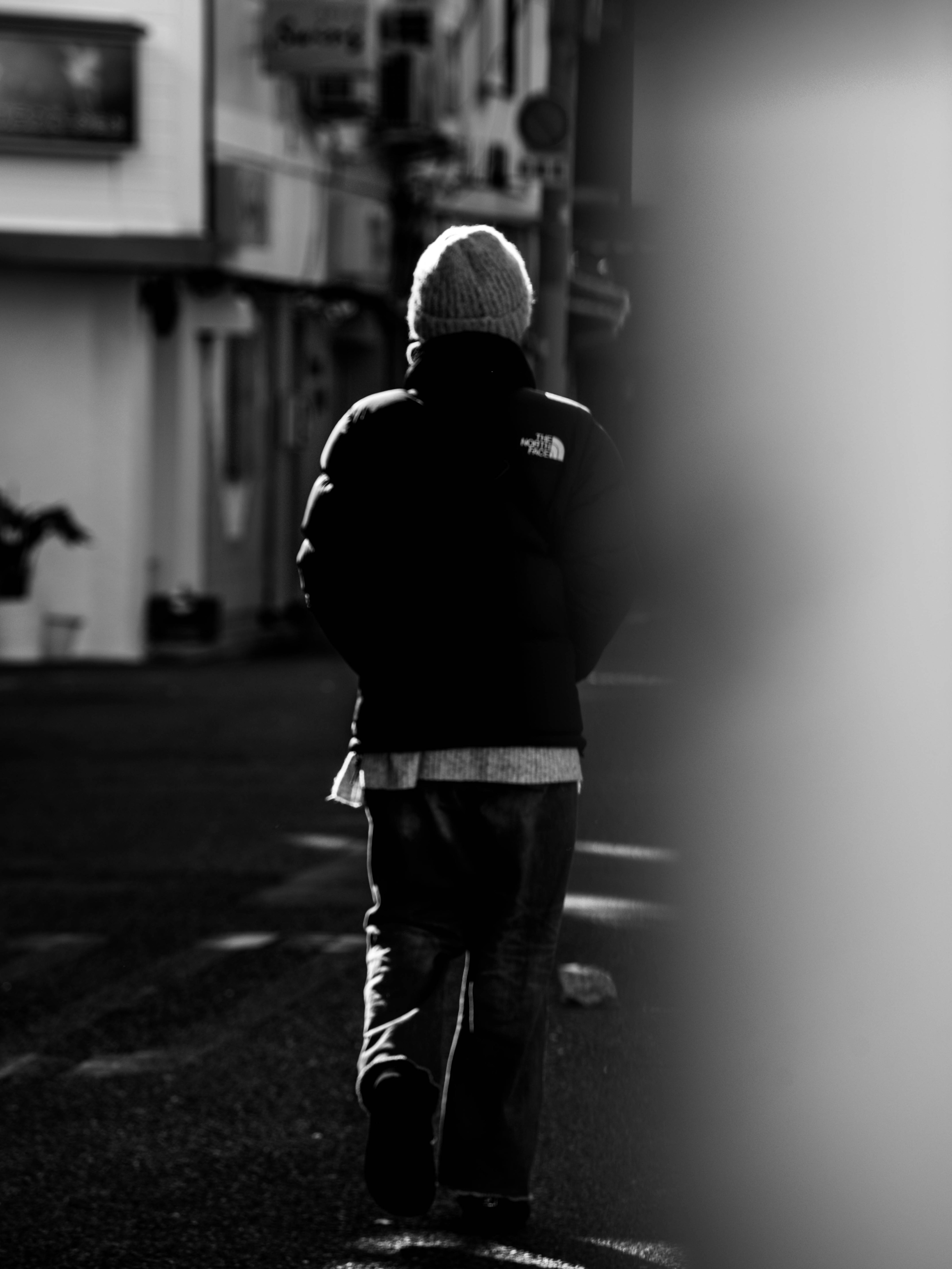 Persona caminando en un entorno urbano en blanco y negro vista desde atrás fondo borroso