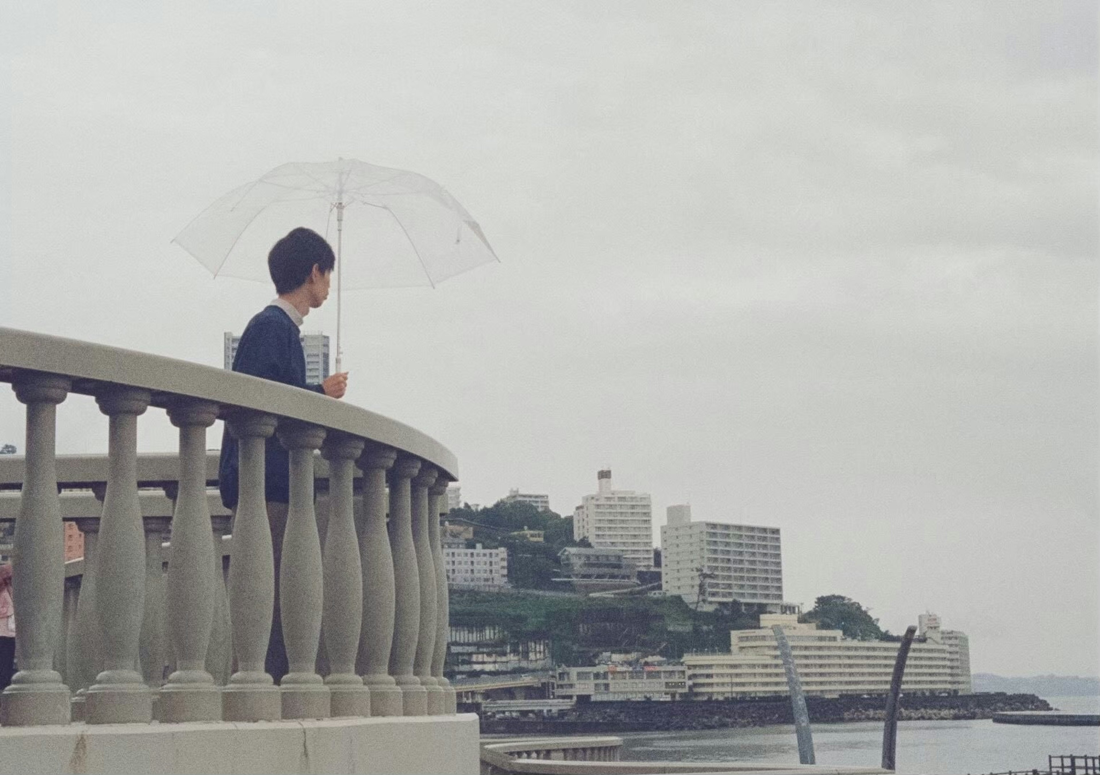 Junge mit einem Regenschirm, der auf das Meer schaut