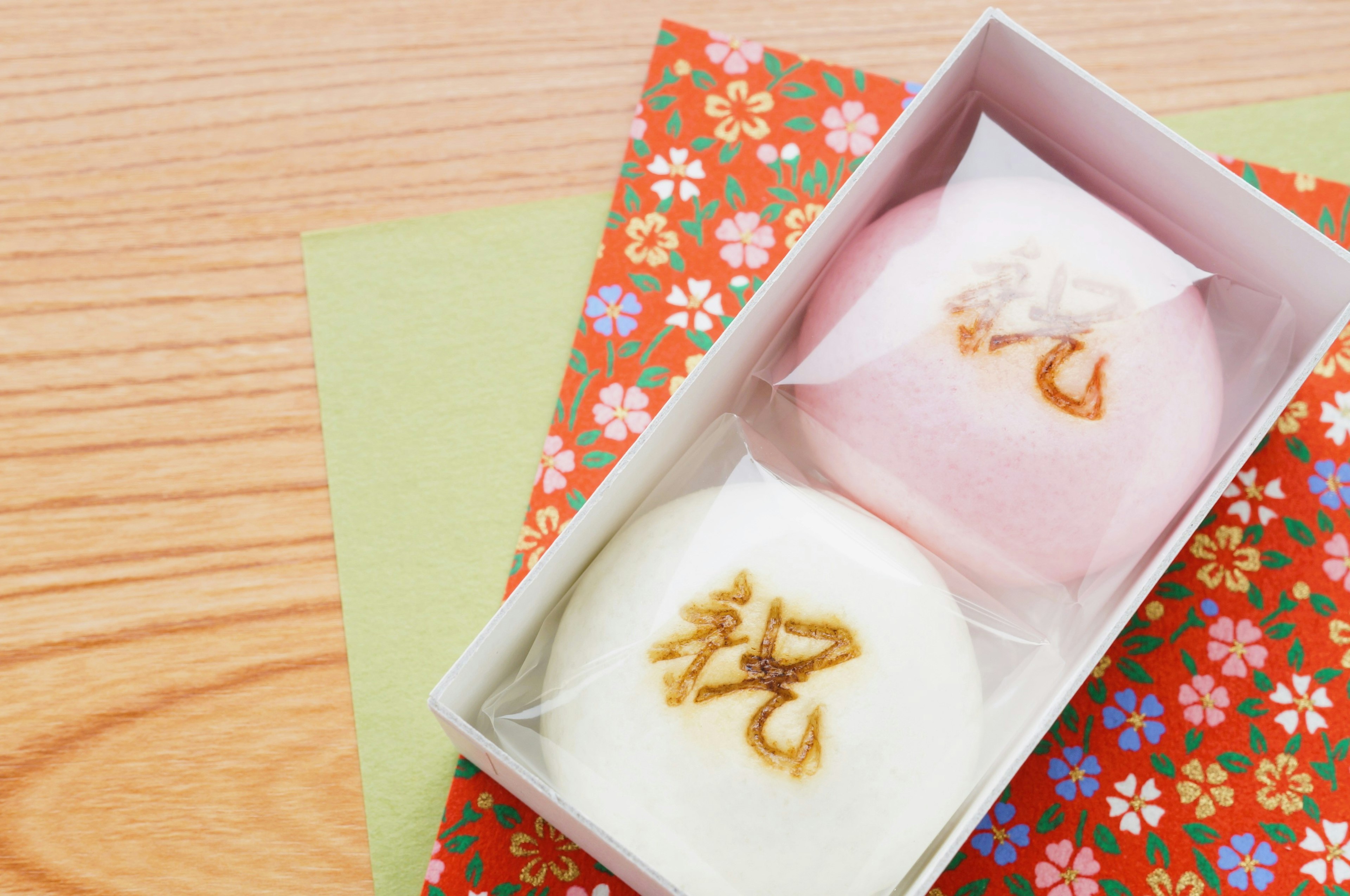 Dos dulces japoneses en una caja sobre un envoltorio de flores