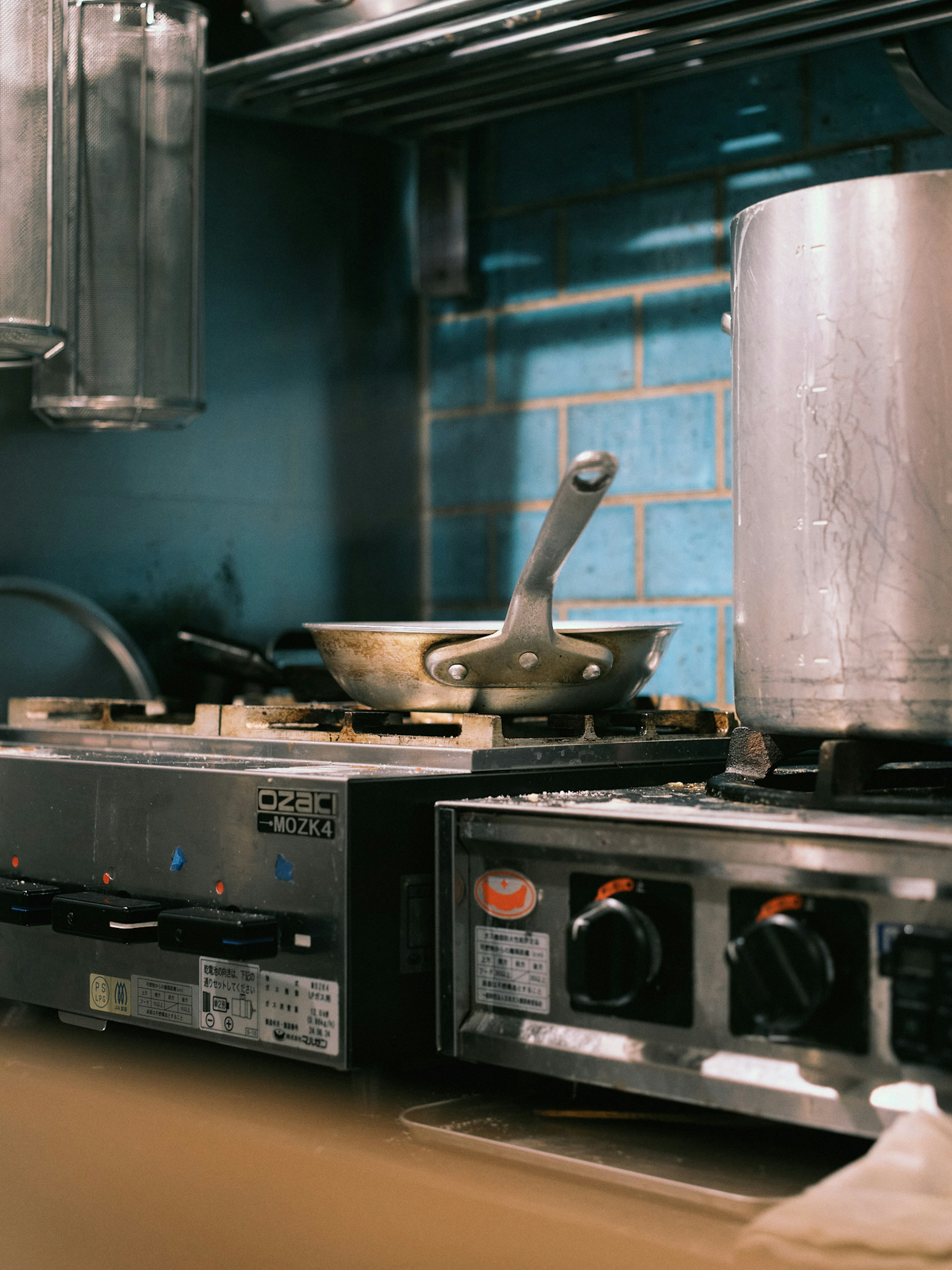 Kitchen stove with a pot and pan against a blue tile wall