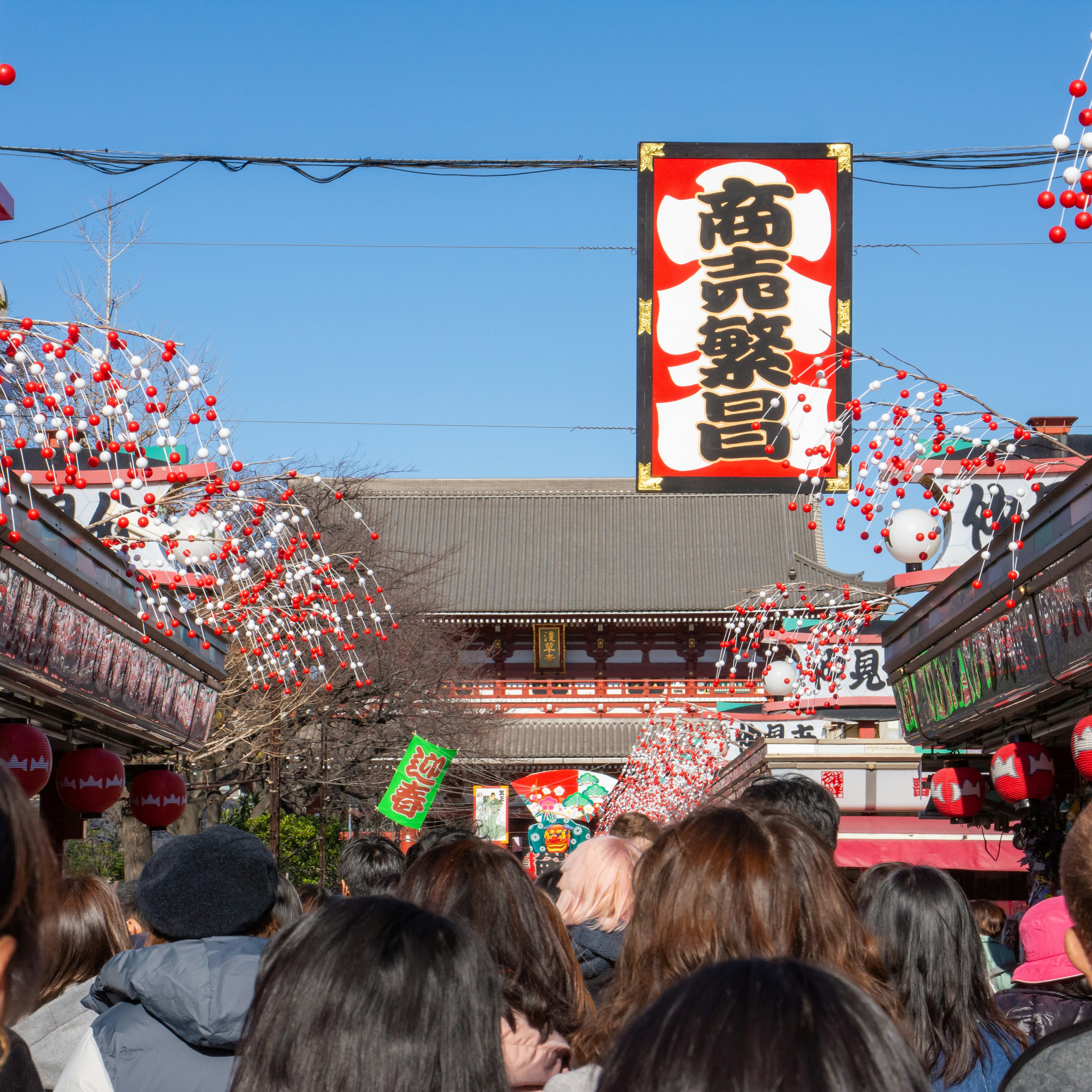 Foule de personnes dans une rue commerçante animée avec ciel bleu et lanternes rouges