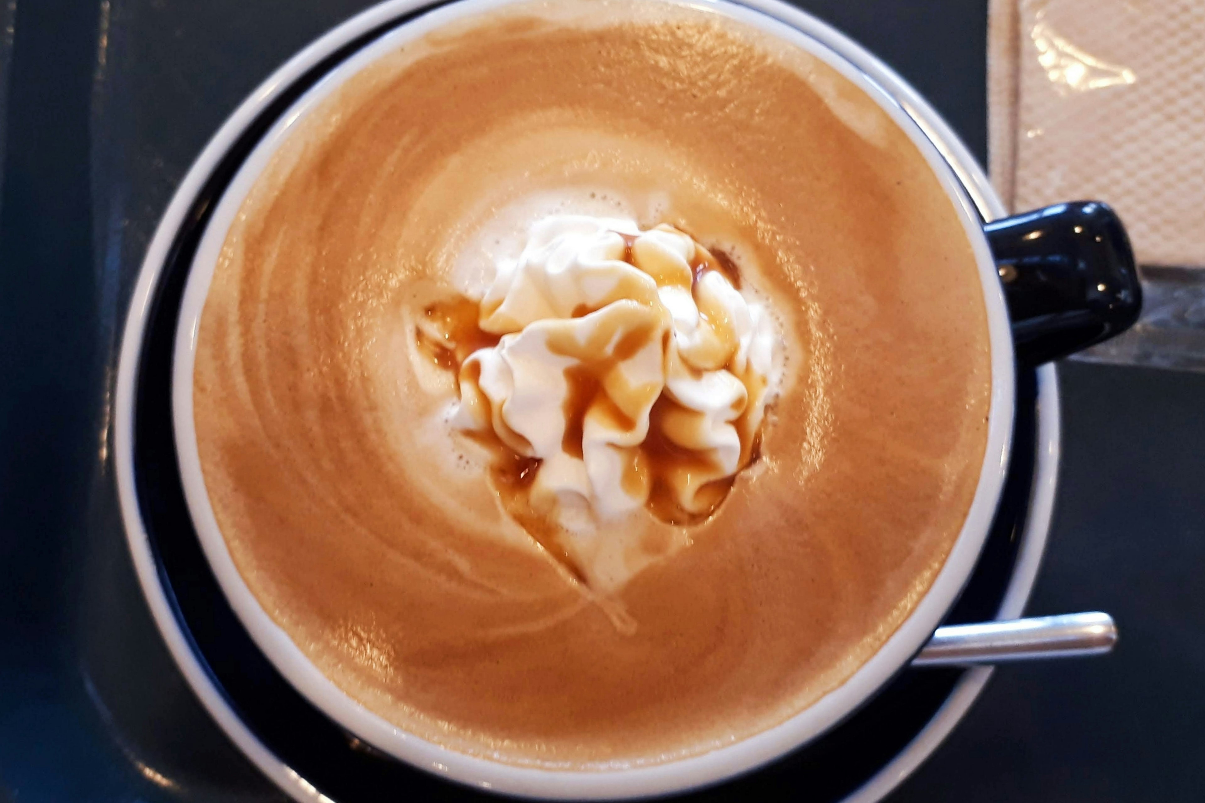 Top view of a latte with whipped cream and syrup topping