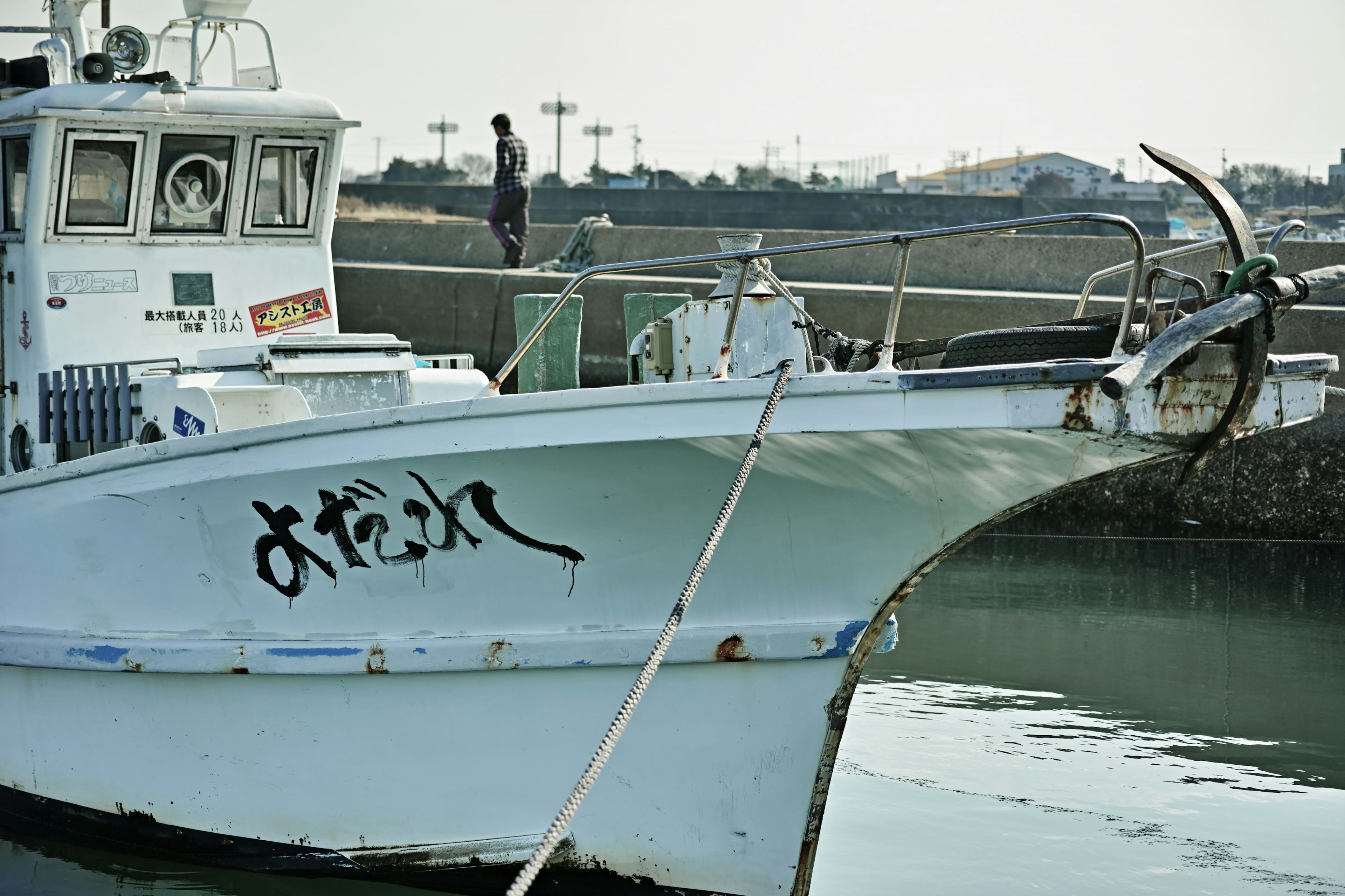 A white fishing boat with Japanese characters on the bow