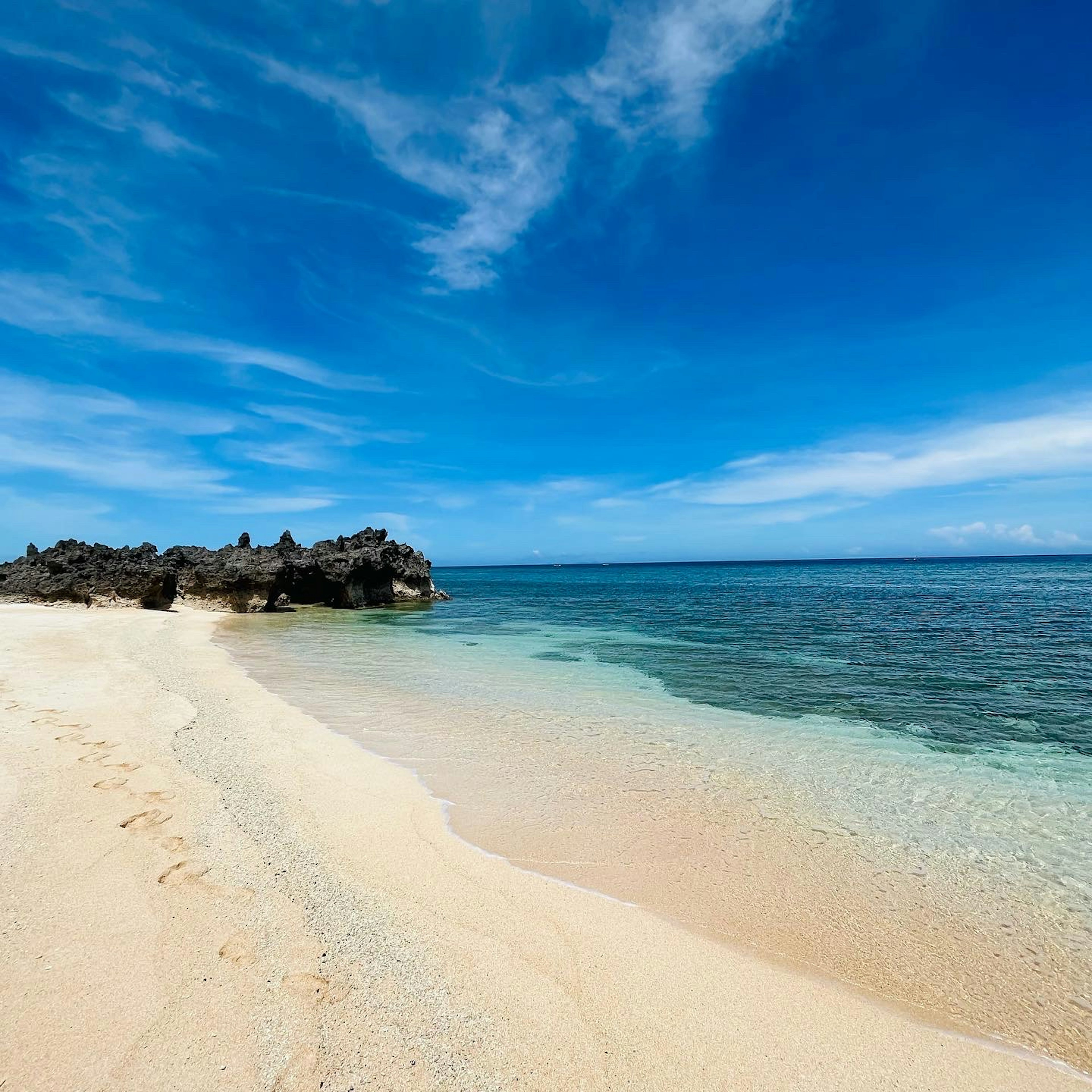 Pemandangan pantai yang indah langit biru air jernih pantai berpasir putih dan batu-batu tersebar