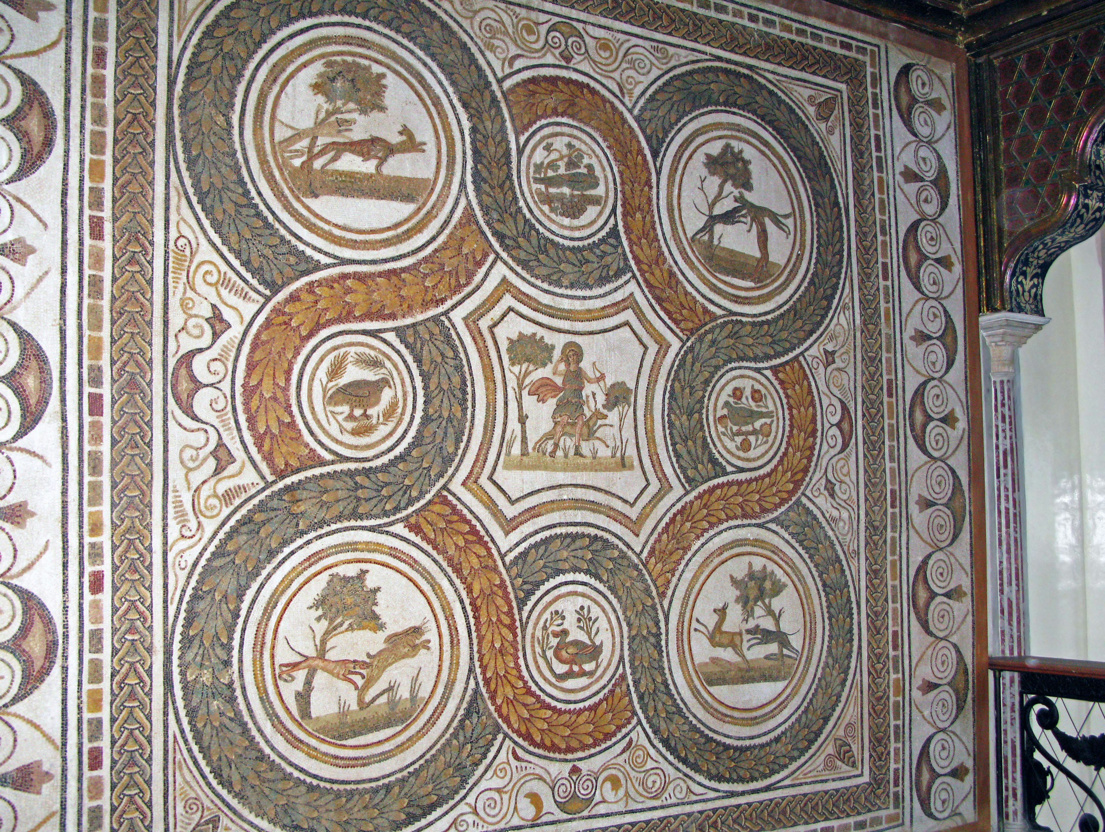 Ancient mosaic art on a wall featuring designs of nature and animals