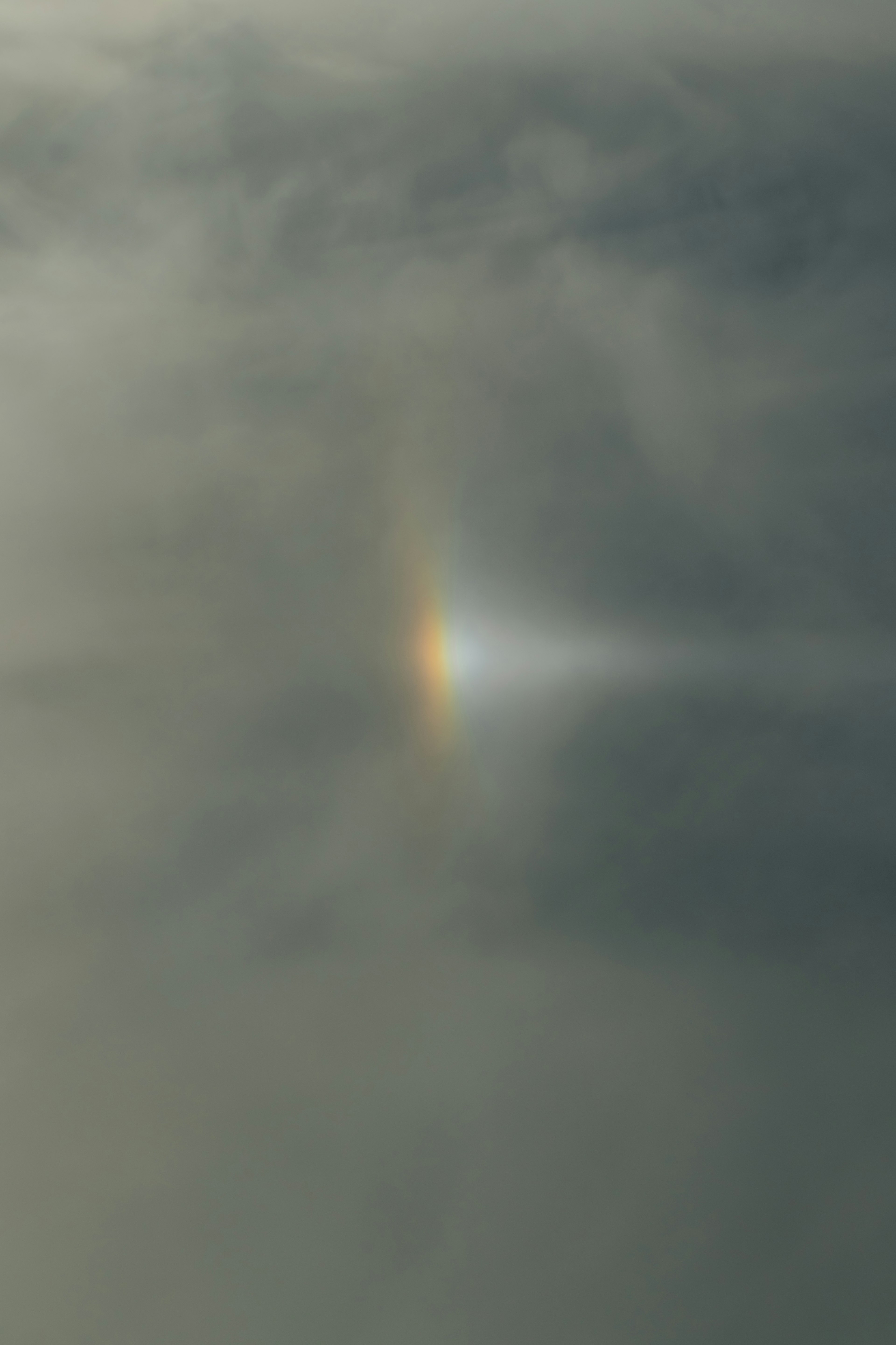 Faint rainbow light appearing through clouds