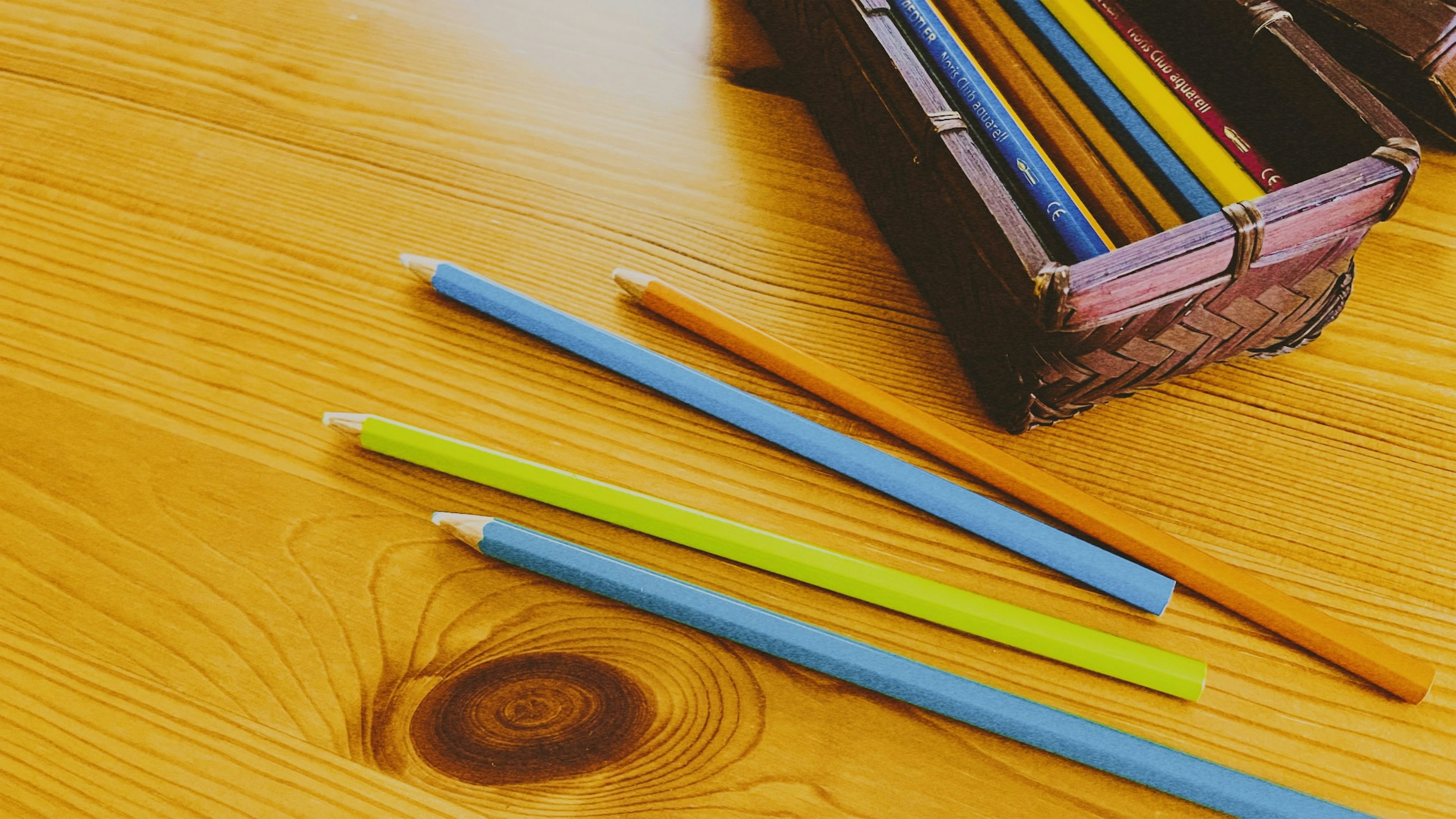 Crayones coloridos y una pequeña caja sobre una mesa de madera