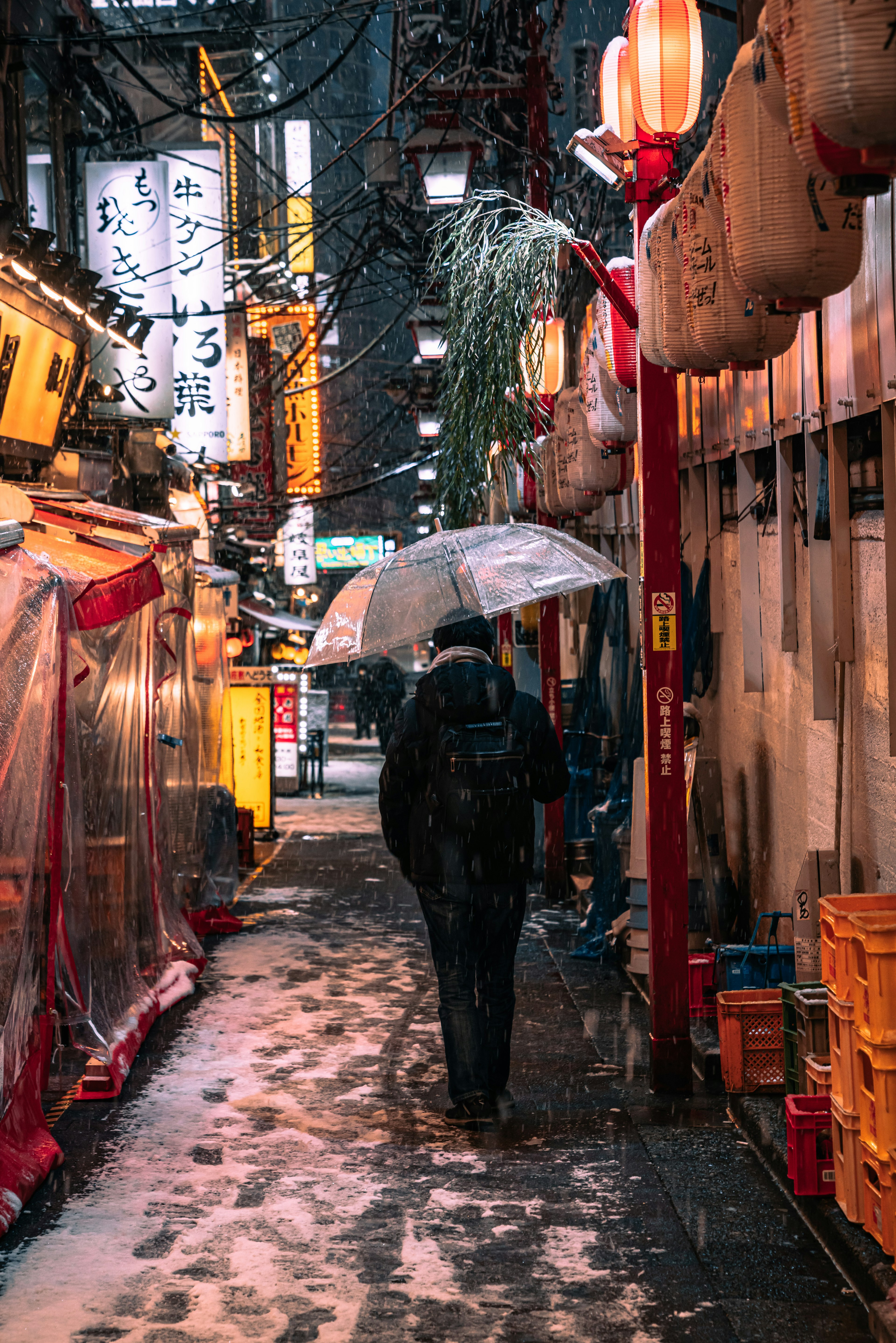 Una persona caminando con un paraguas en un callejón nevado de Tokio por la noche