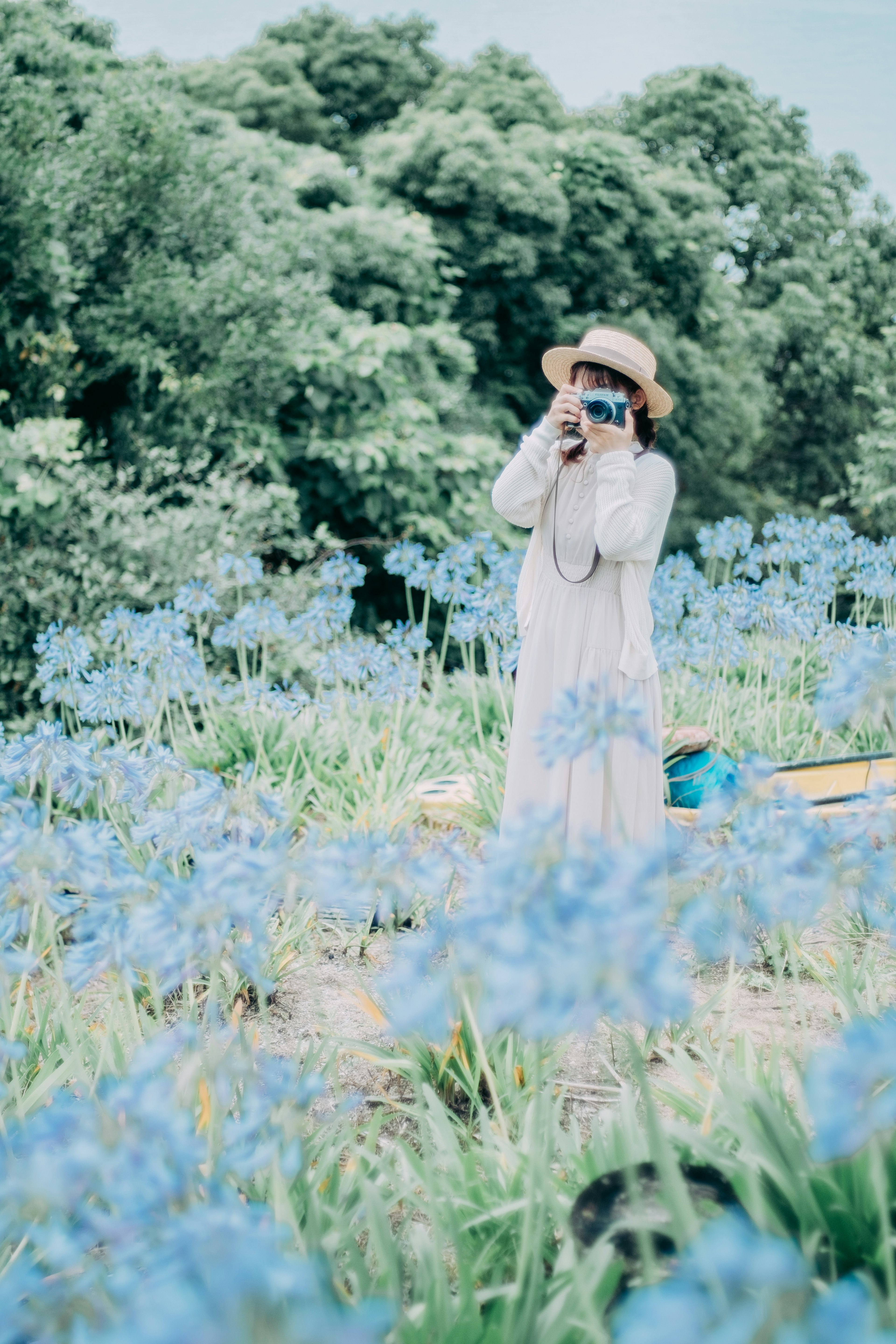 Mujer sosteniendo una cámara rodeada de flores azules