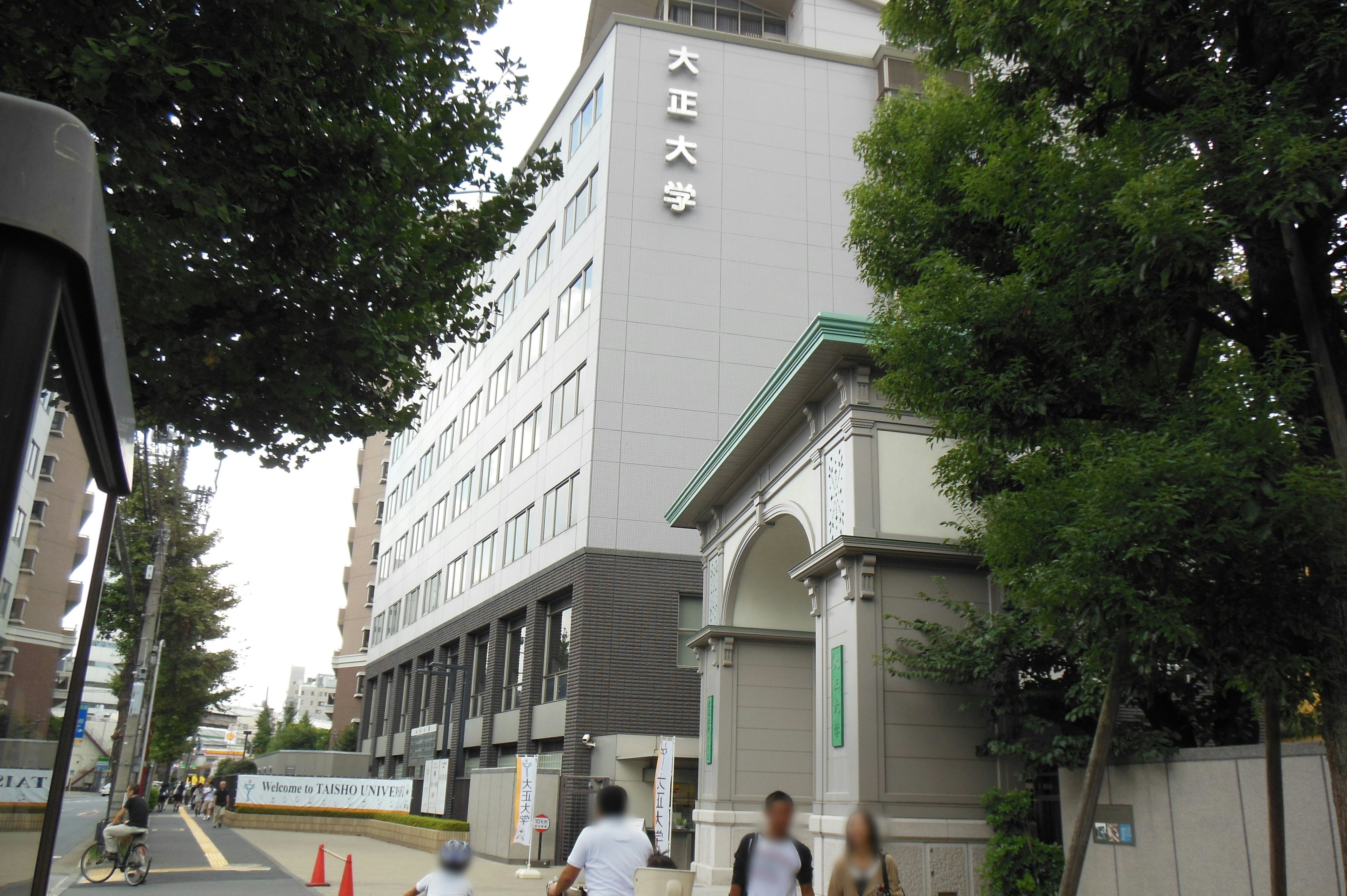 Pedestrians approaching the exterior of a university building in Tokyo