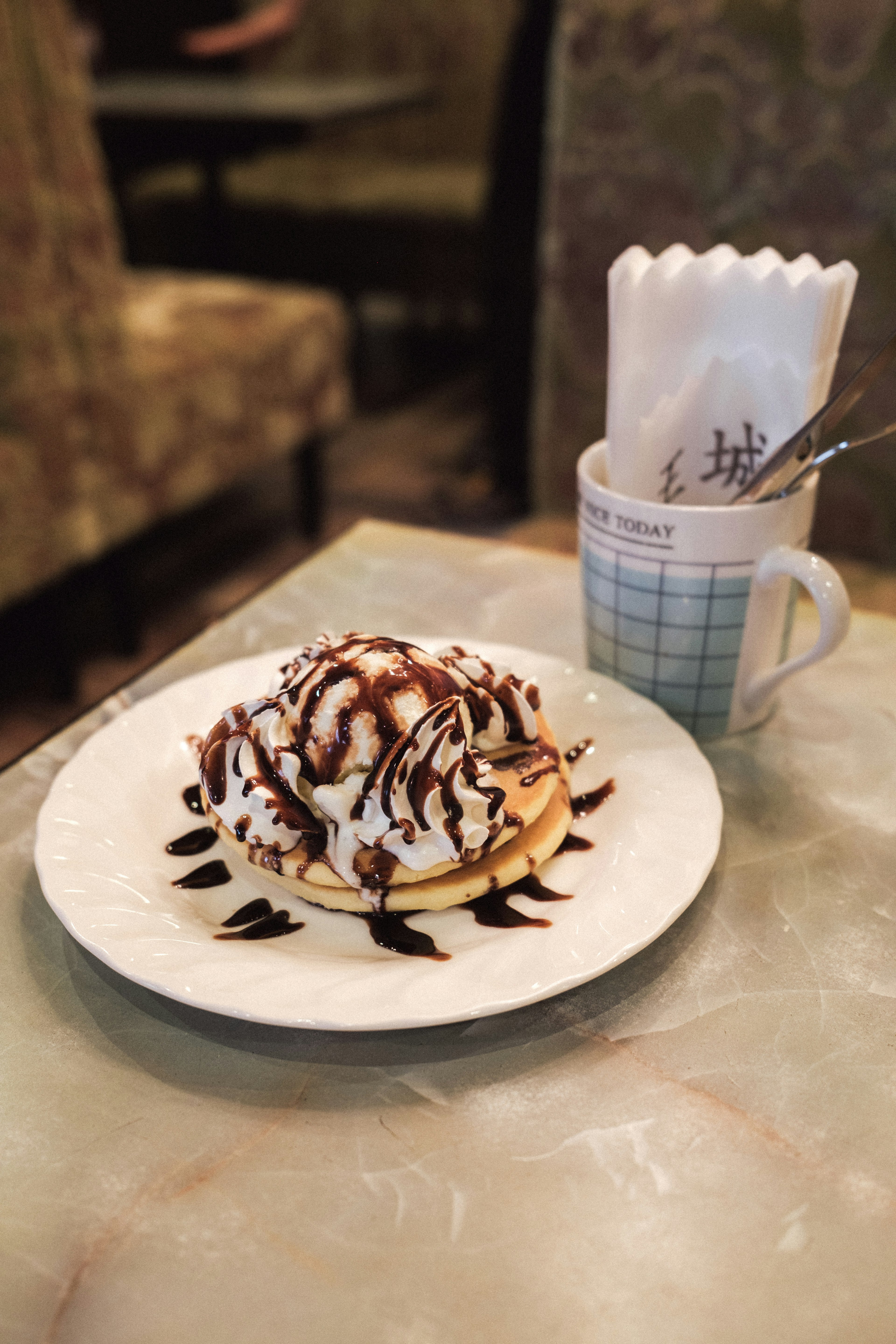 Pancake topped with chocolate sauce and whipped cream on a plate