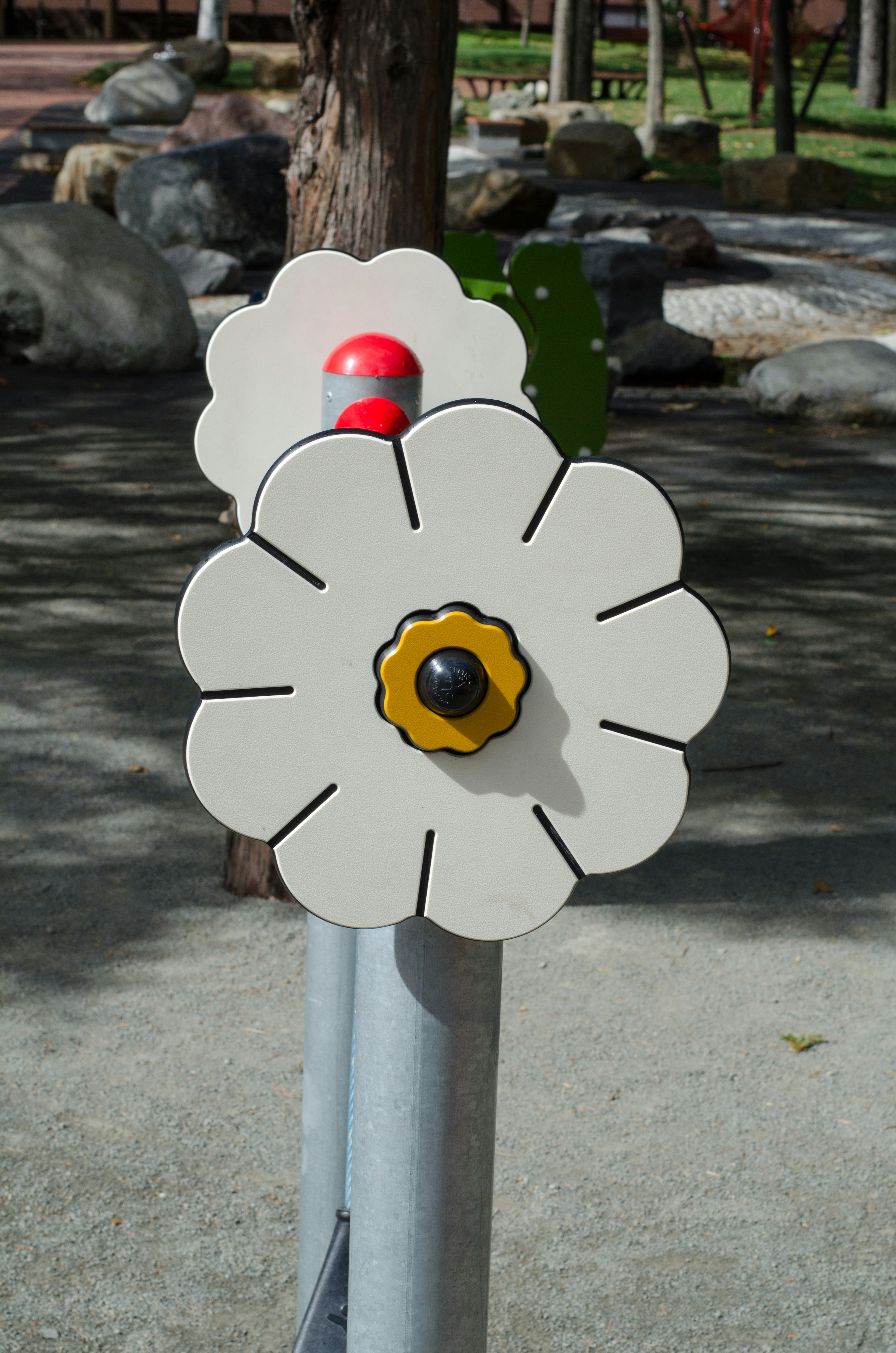 Spielplatzgerät in Blumenform mit roten Bällen und gelbem Zentrum