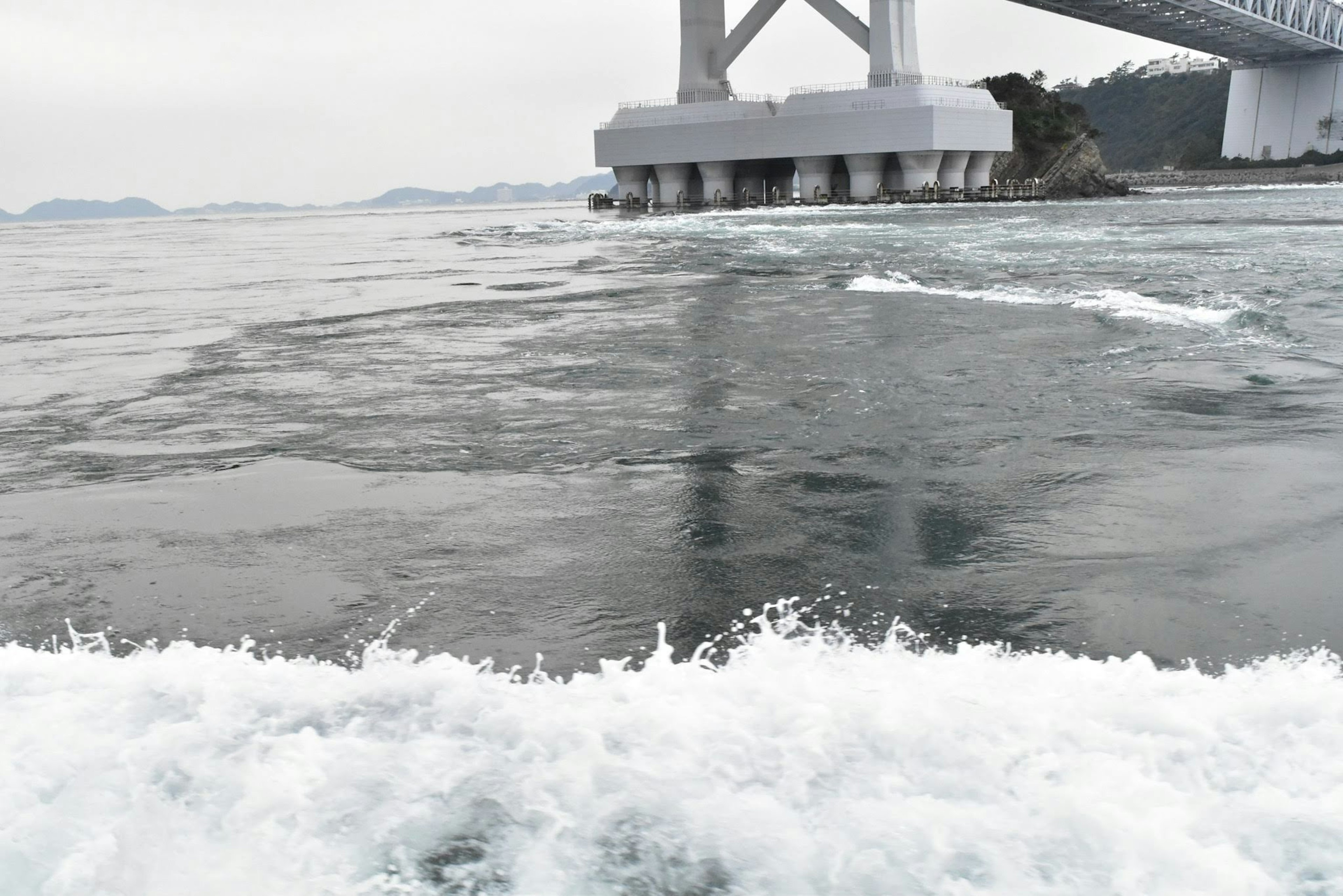 Olas en el océano con un puente al fondo