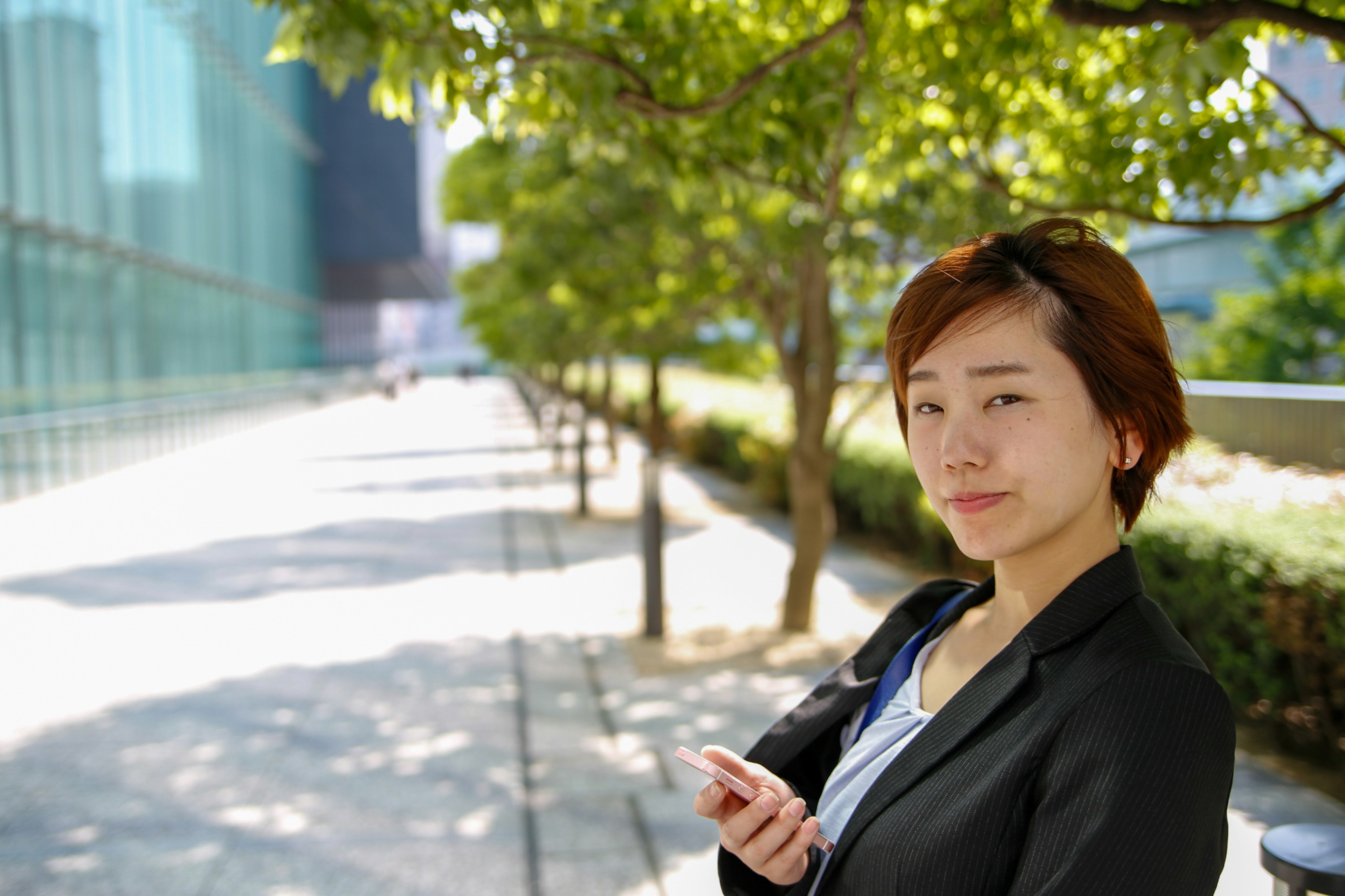 在绿色树木间站立的女性商务人士的肖像