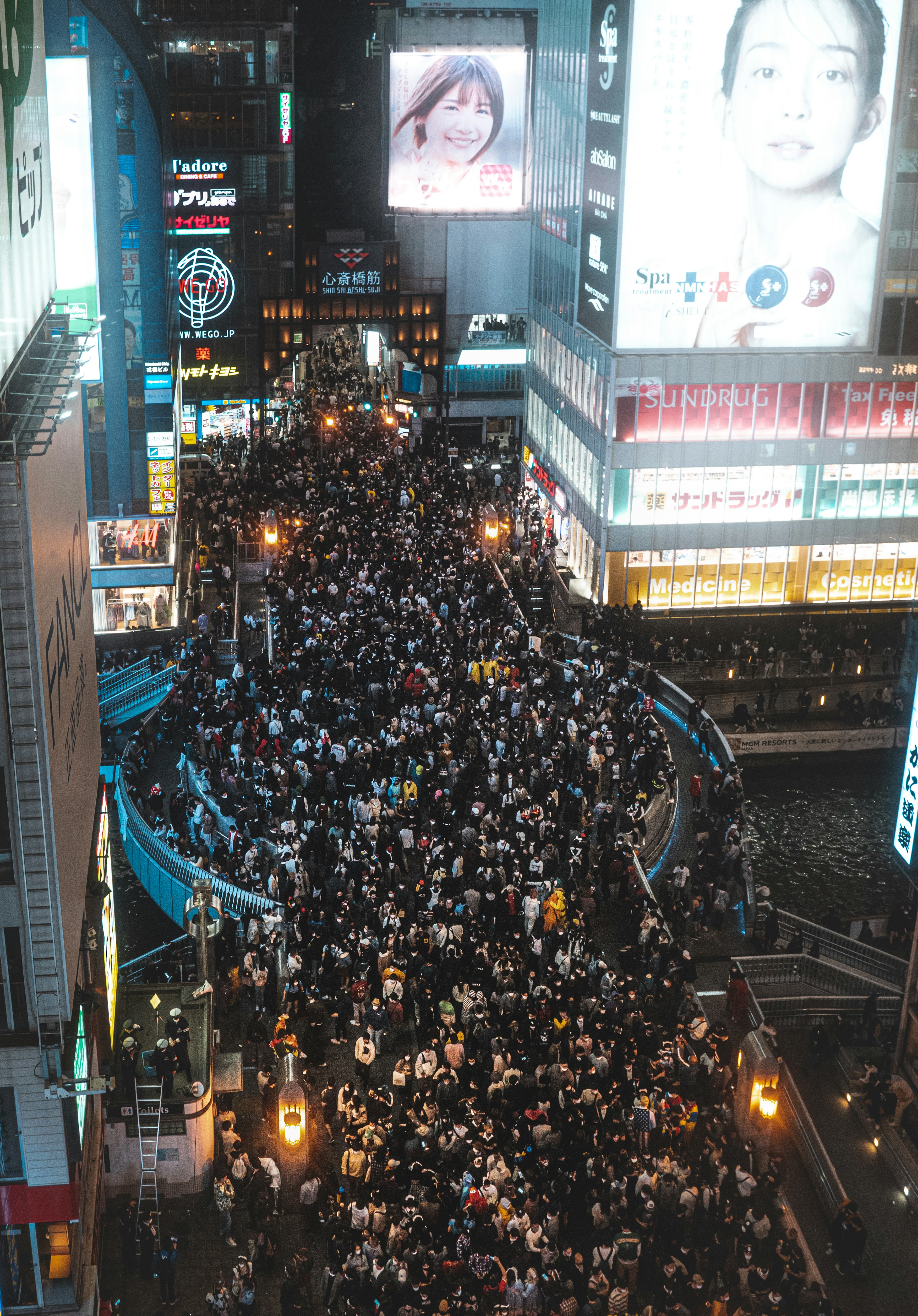 Menschenmenge an der Shibuya-Kreuzung bei Nacht mit hellen Werbungen