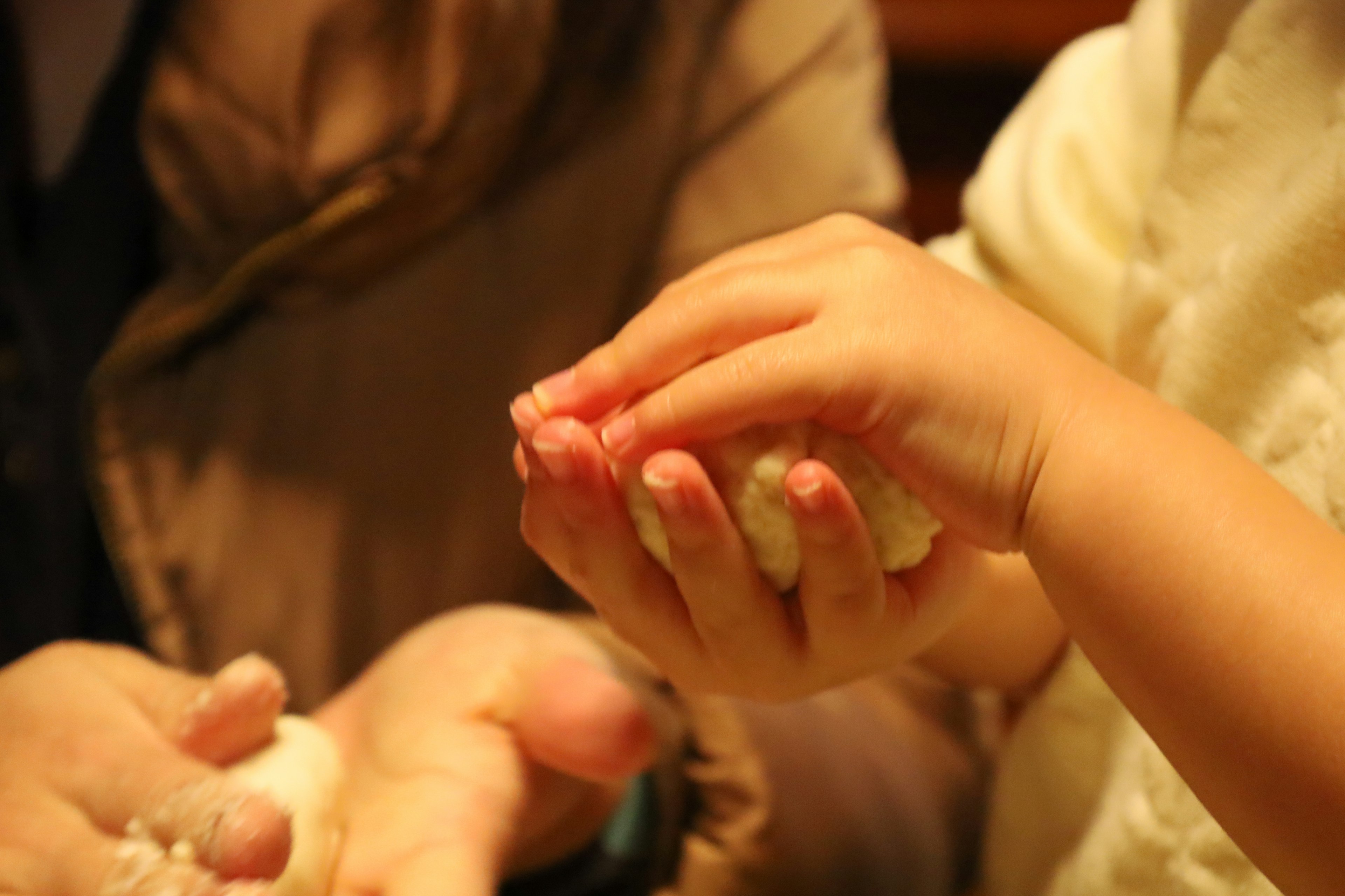 Una mano di bambino che tiene del cibo con una mano di adulto vicina