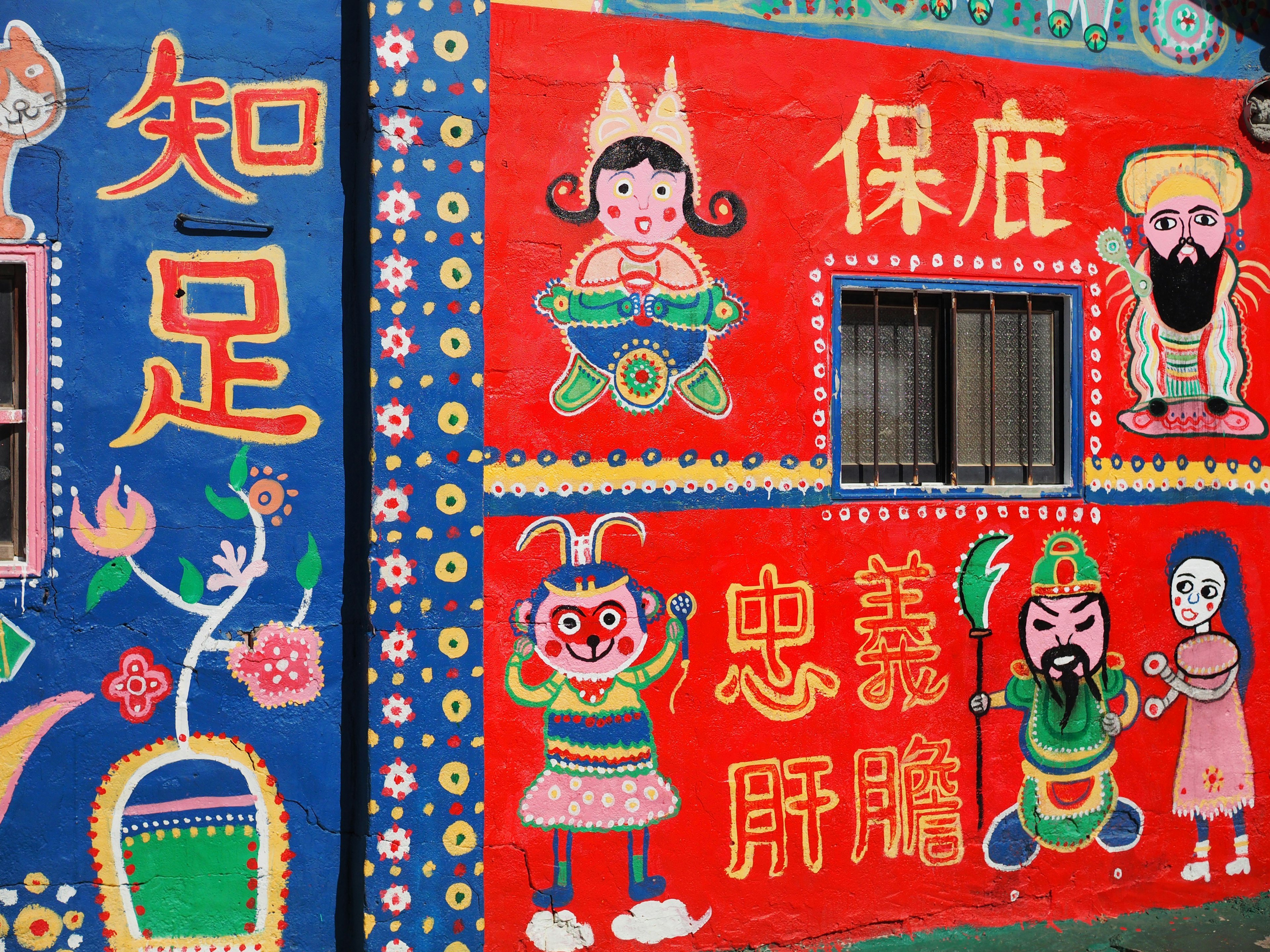 Colorful wall murals featuring characters and Chinese characters on a building exterior