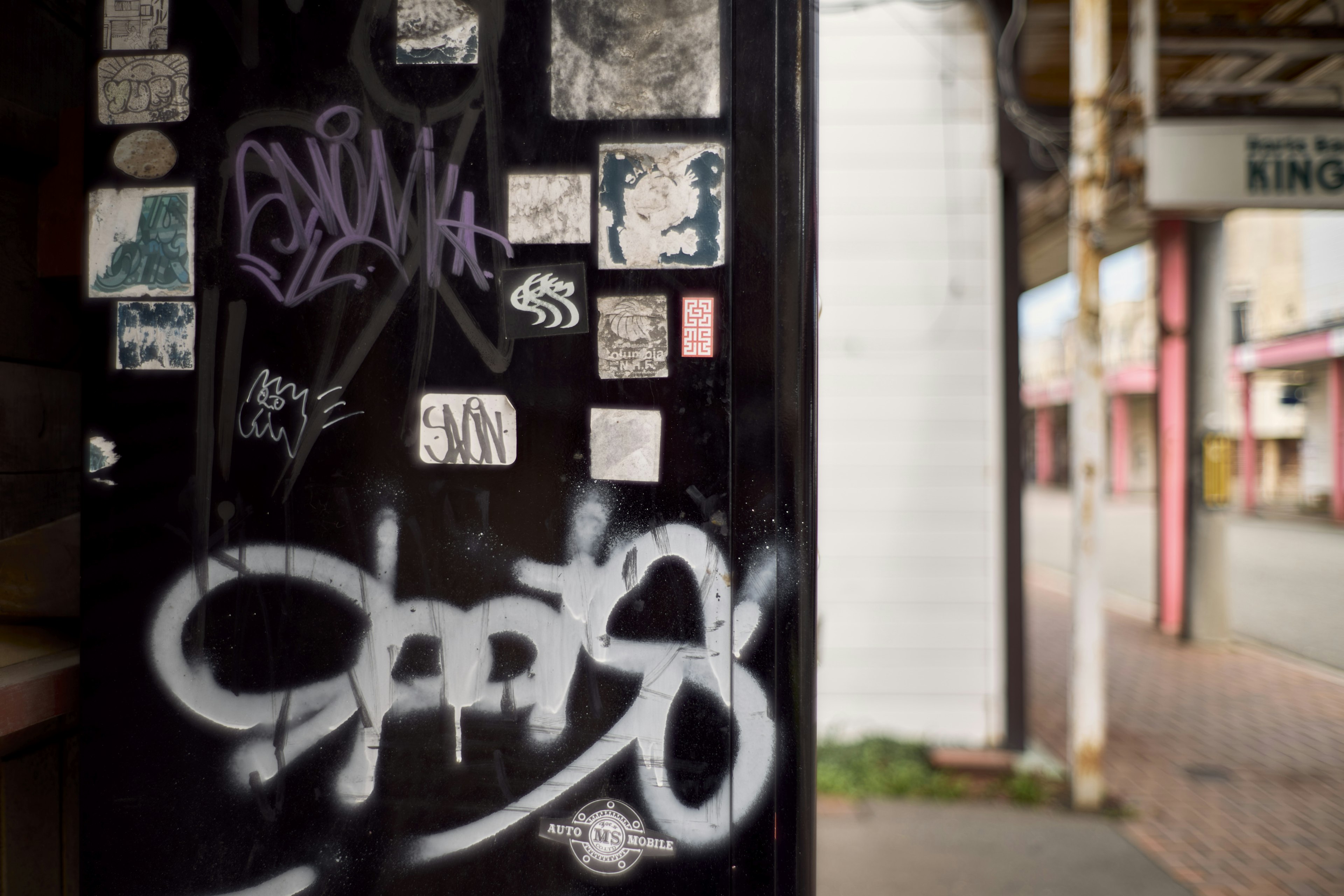 Scena urbana con un muro nero coperto di graffiti colorati e adesivi