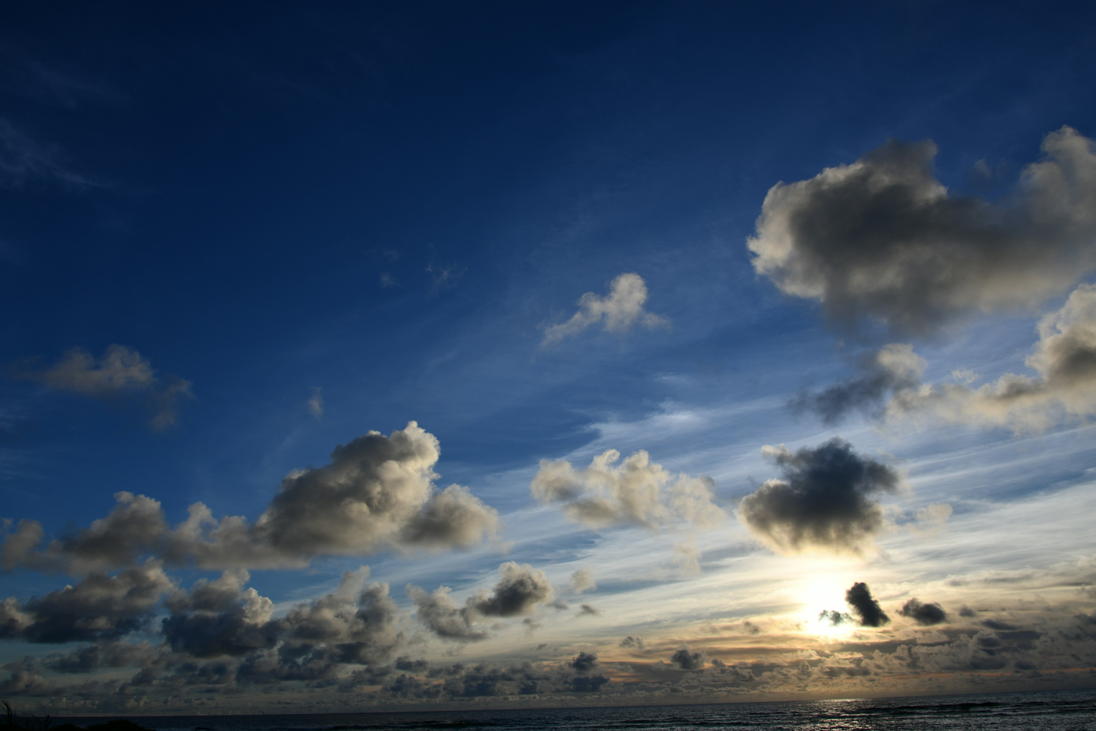 Seascape featuring clouds in a blue sky and a sunset