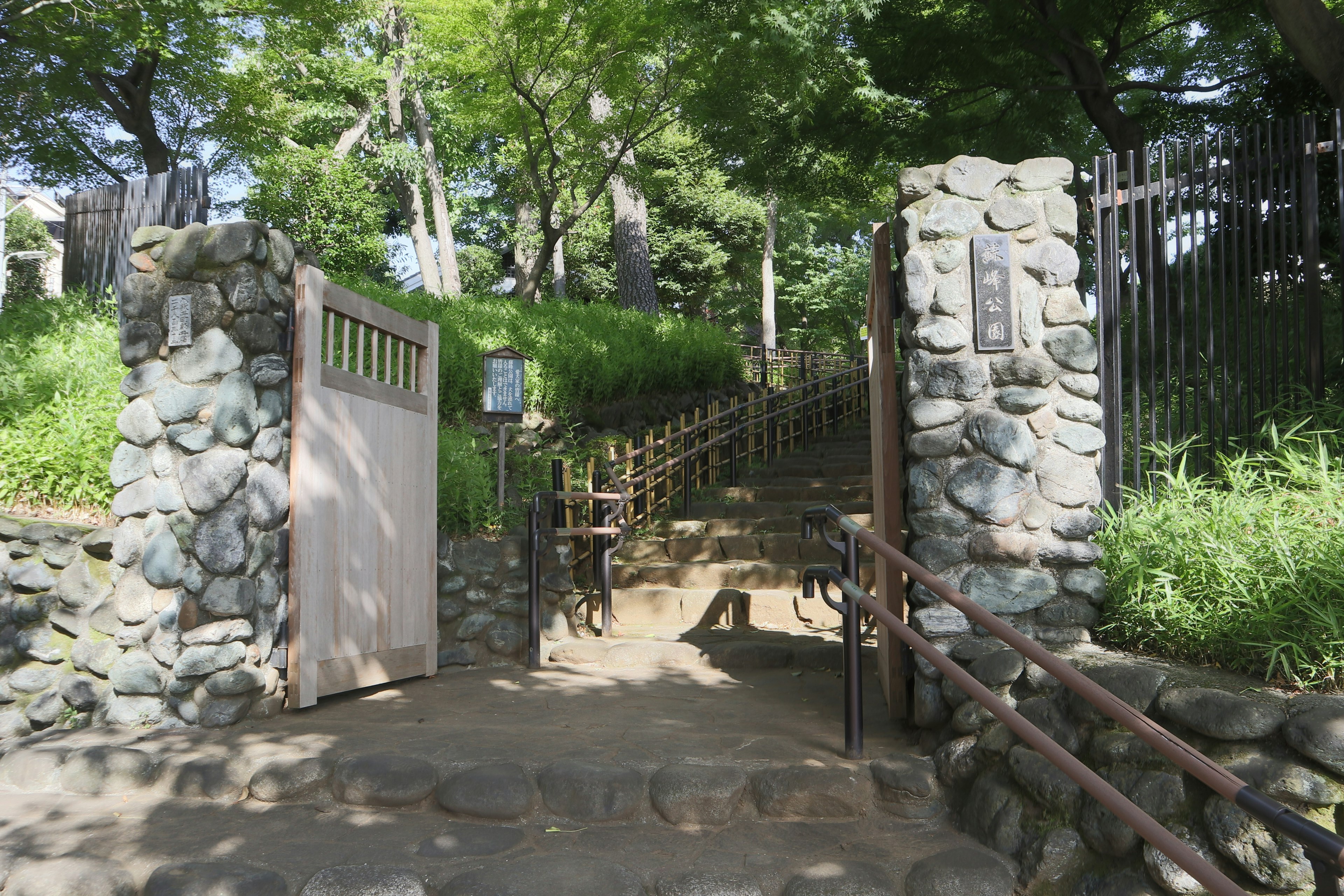 Puerta de piedra con escaleras que conducen a un parque verde