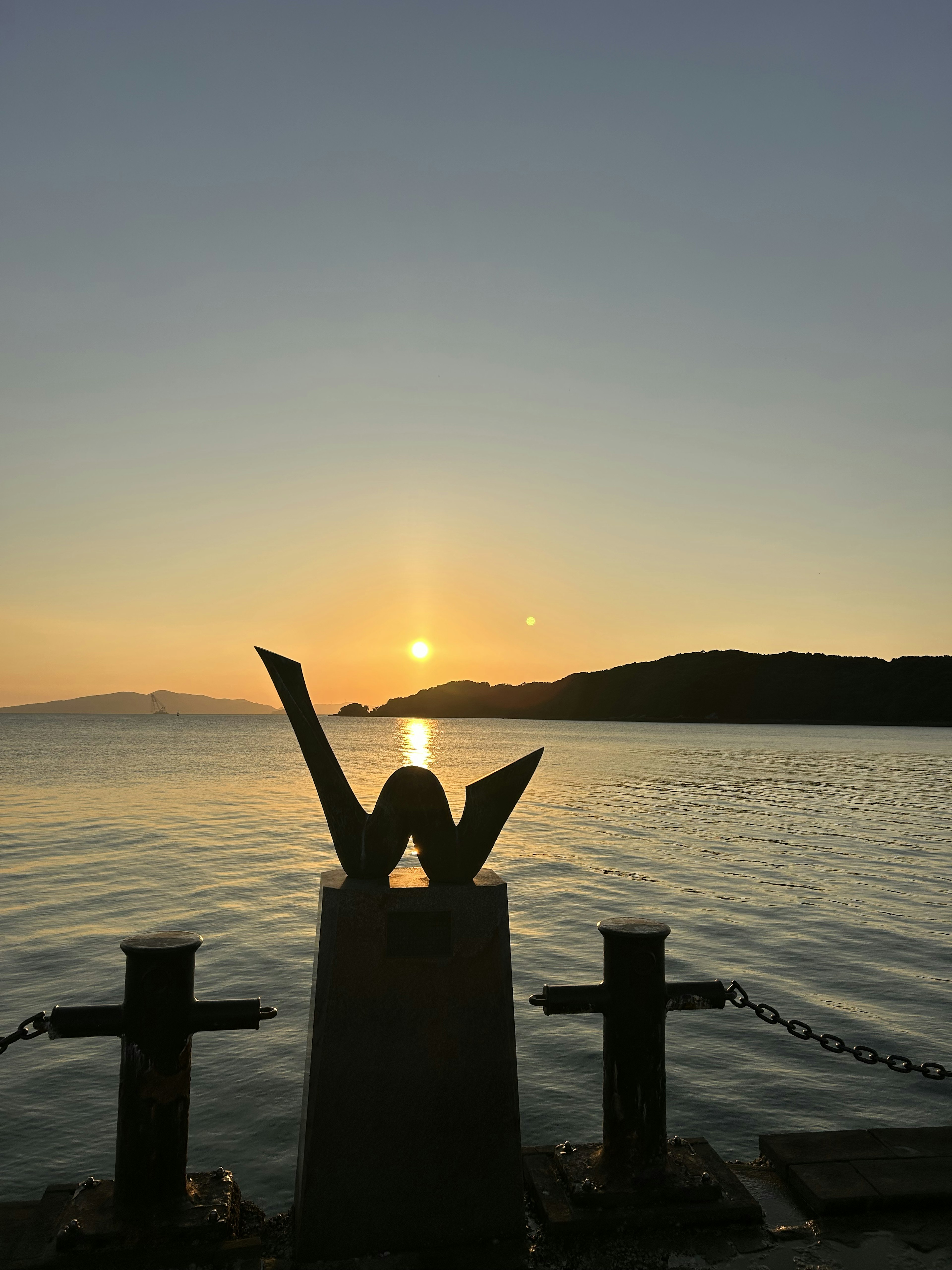 夕日が海に沈む風景とシンボル的な彫刻