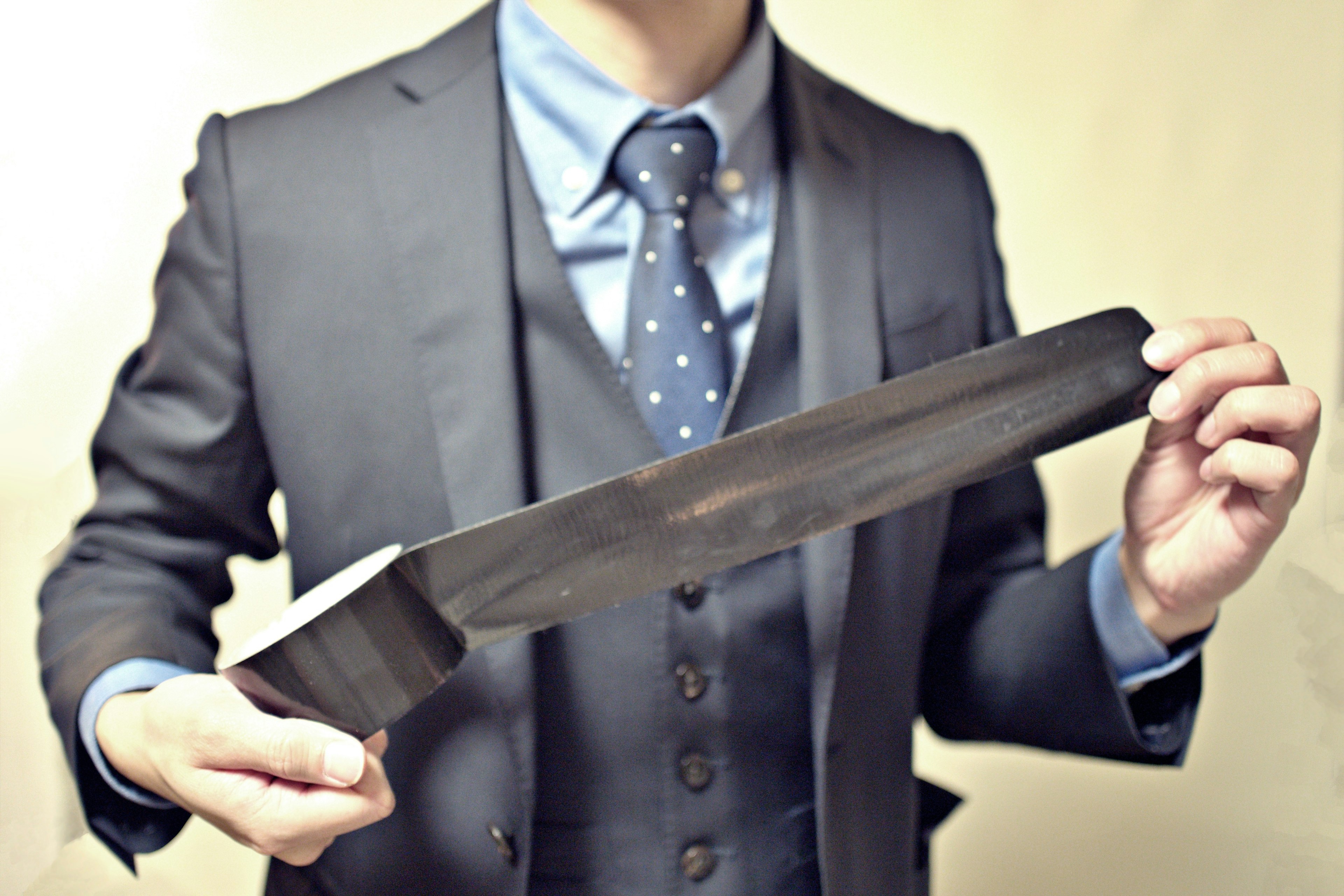 A man in a suit holding a large knife