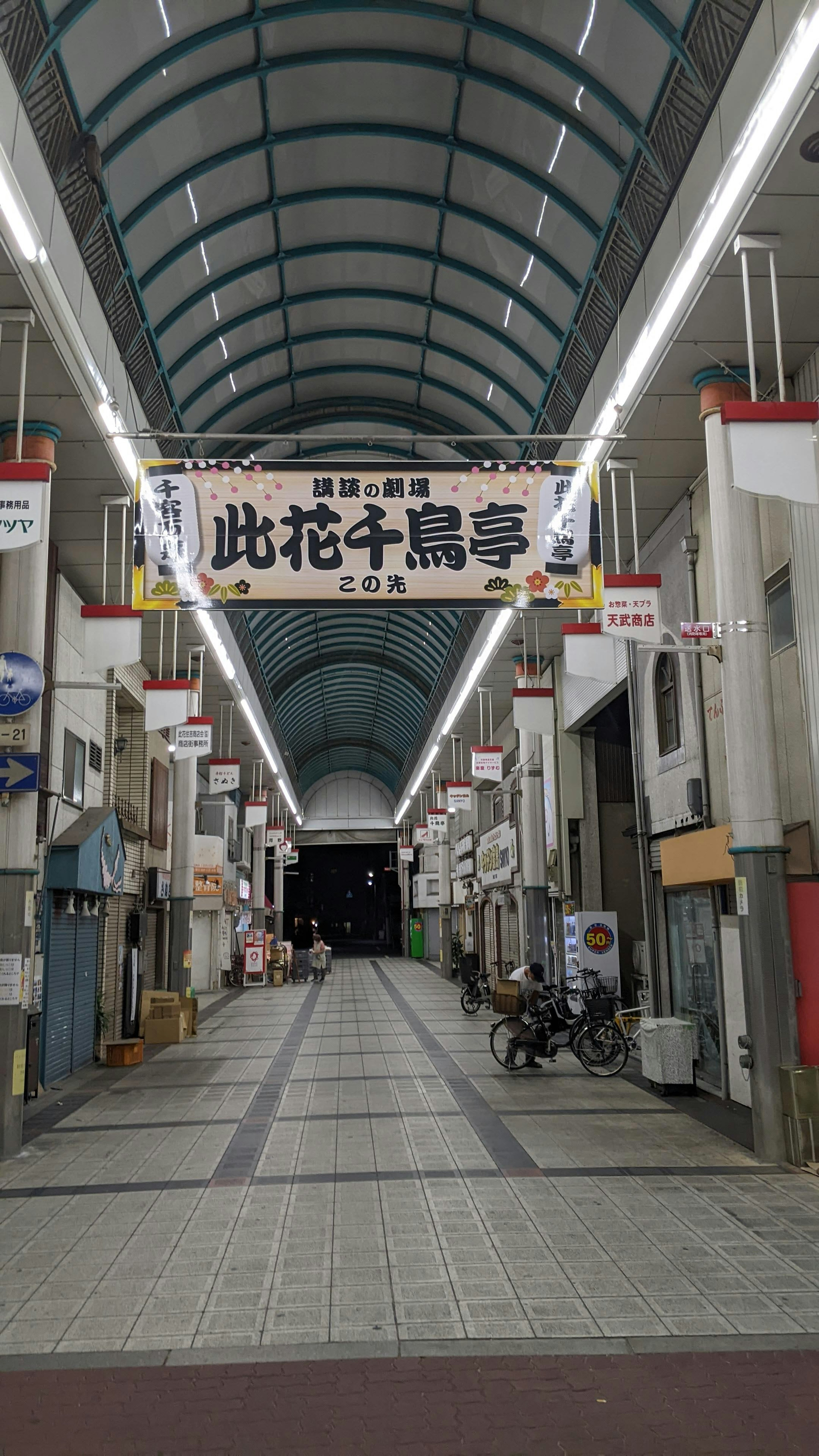 View of a shopping arcade street featuring a long illuminated passage and shop entrances