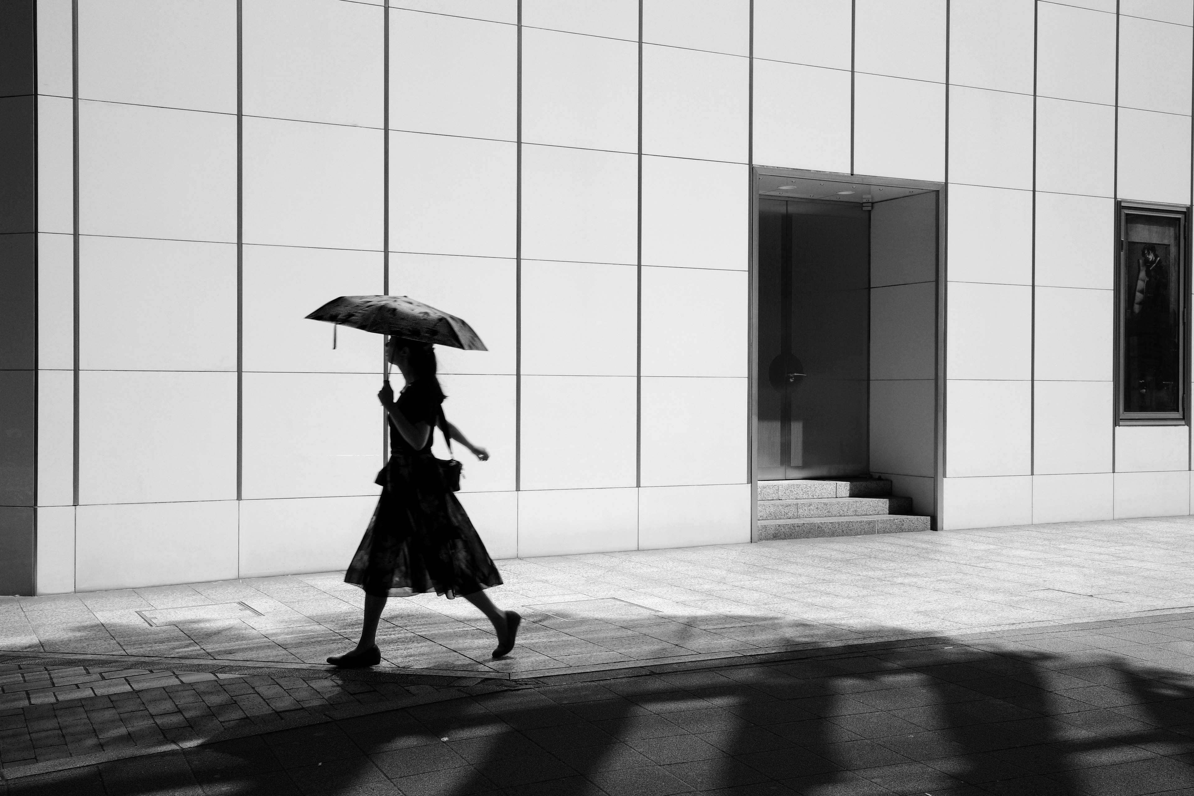 A woman walking with an umbrella in a black and white urban setting