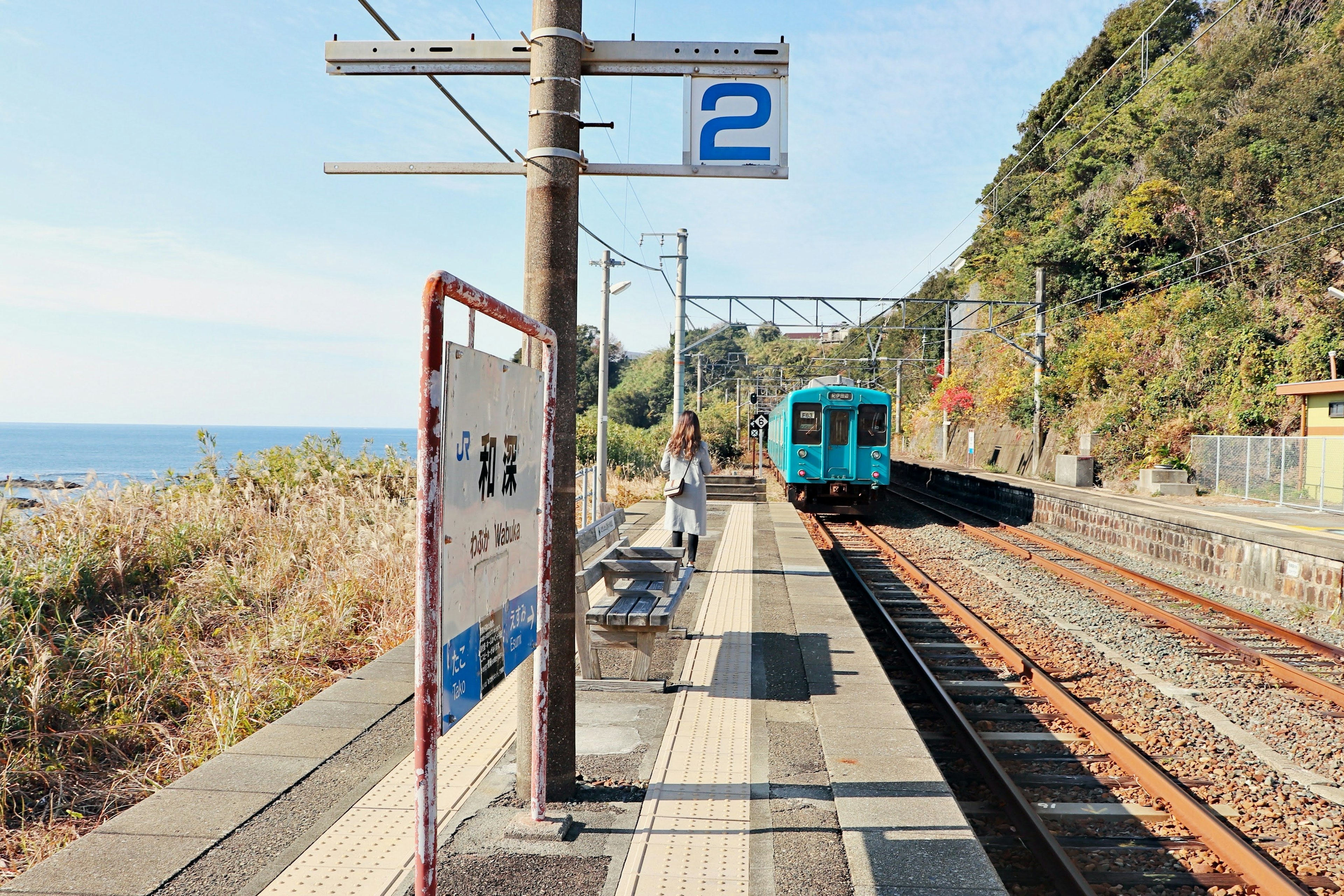 Zugplattform nahe dem Meer mit einem blauen Zug