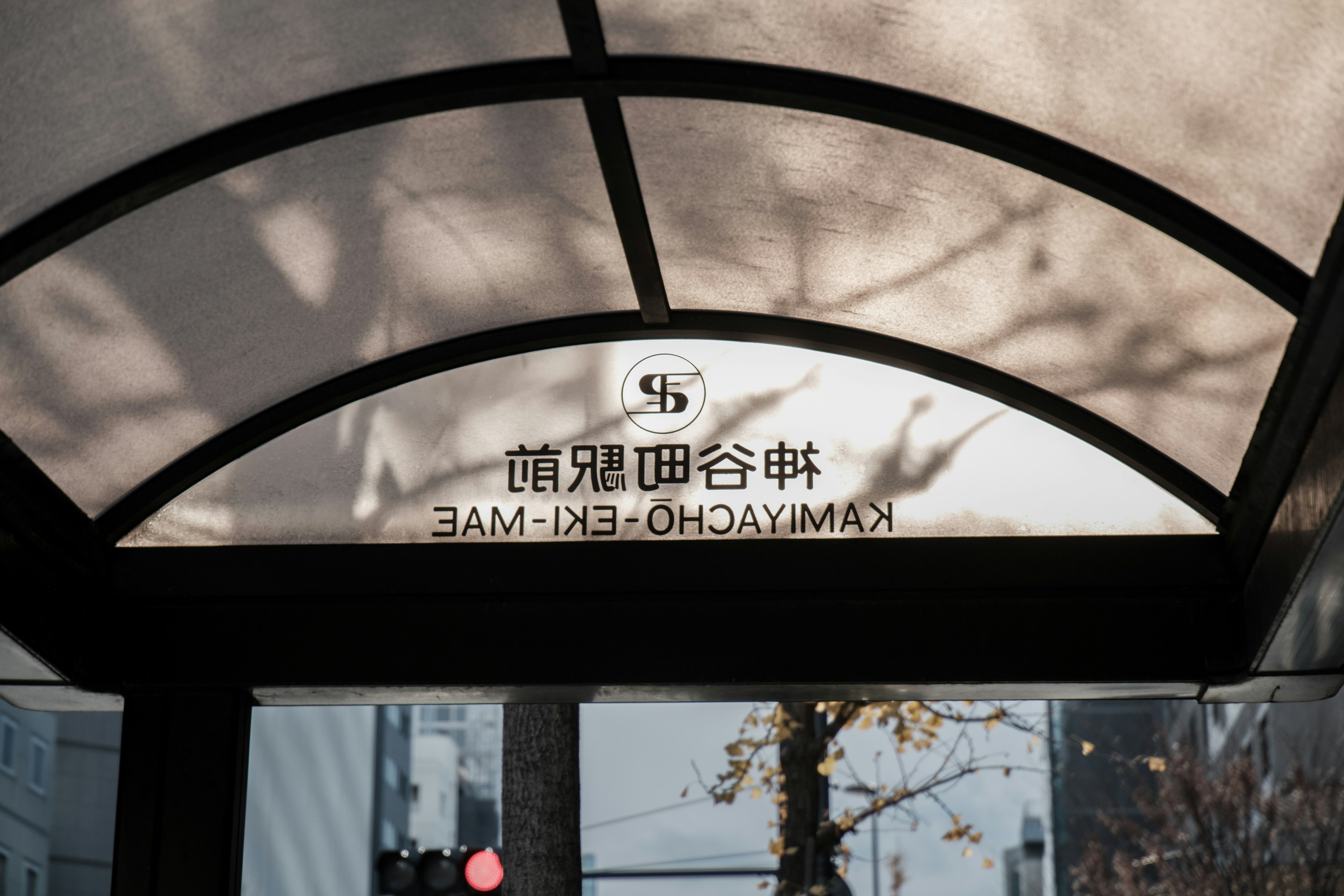 この画像は、神奈川県横浜市の駅の看板で、日差しが差し込む中に影が映っています