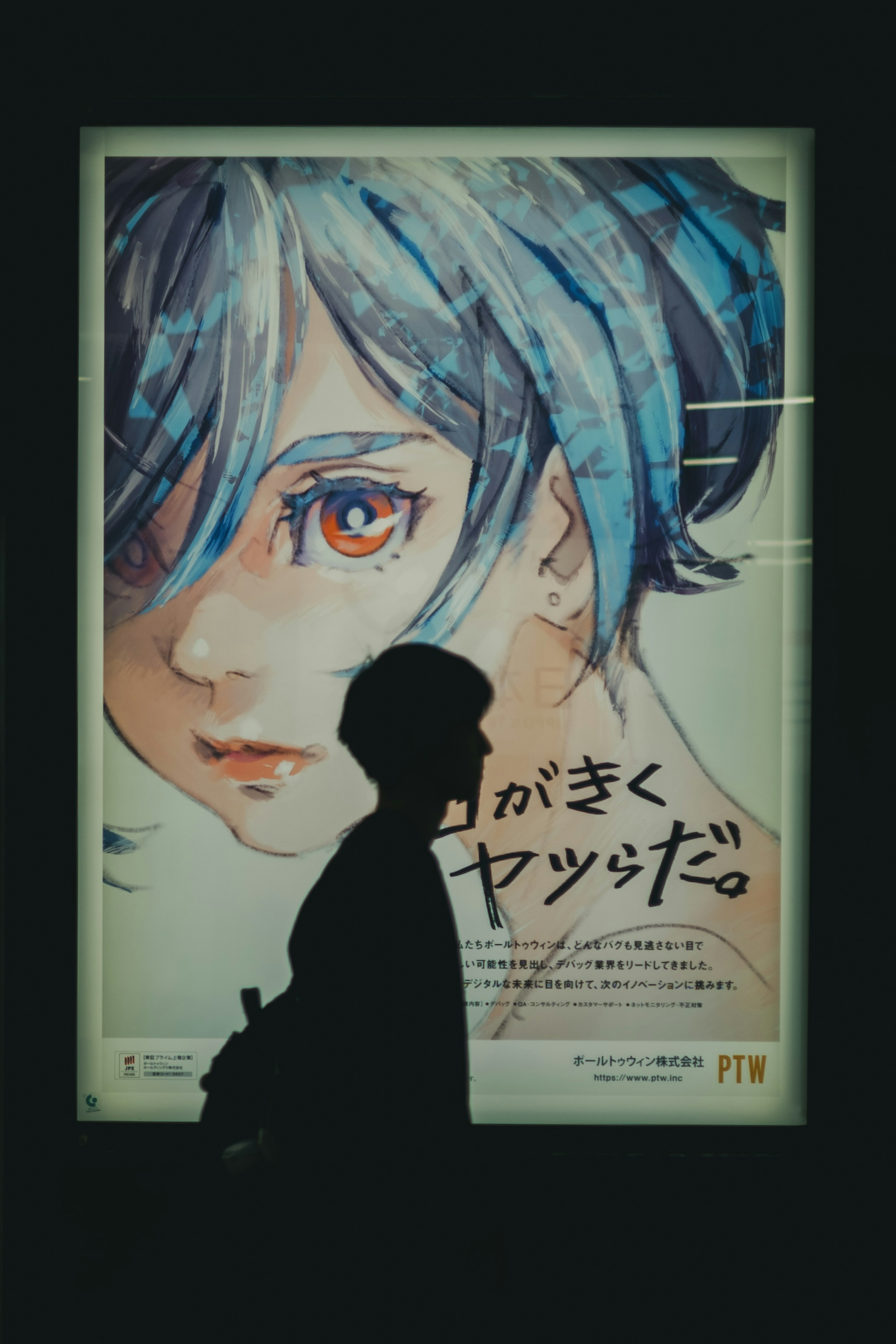 Silhouette d'une personne passant devant une affiche d'une femme aux cheveux bleus