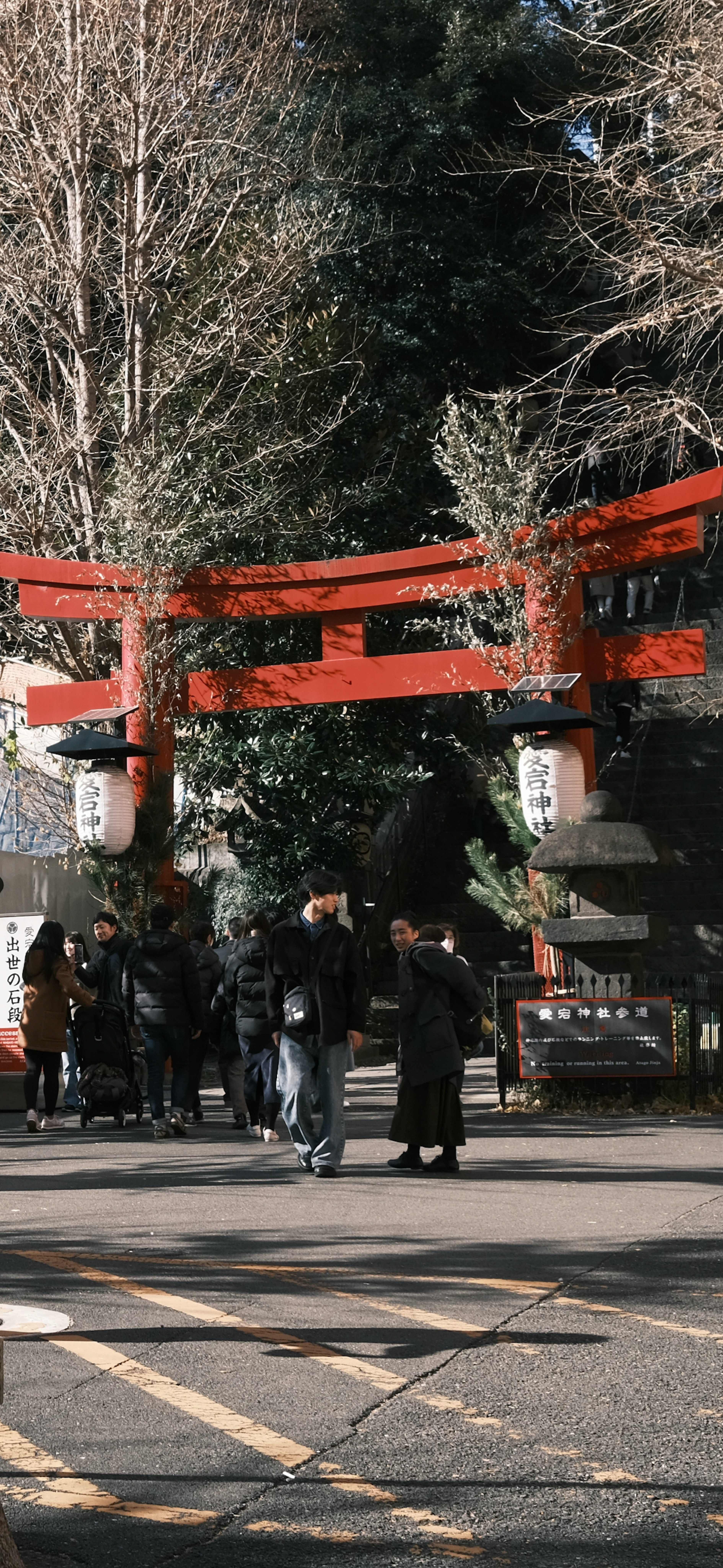 Persone riunite sotto un portale torii rosso circondato da alberi