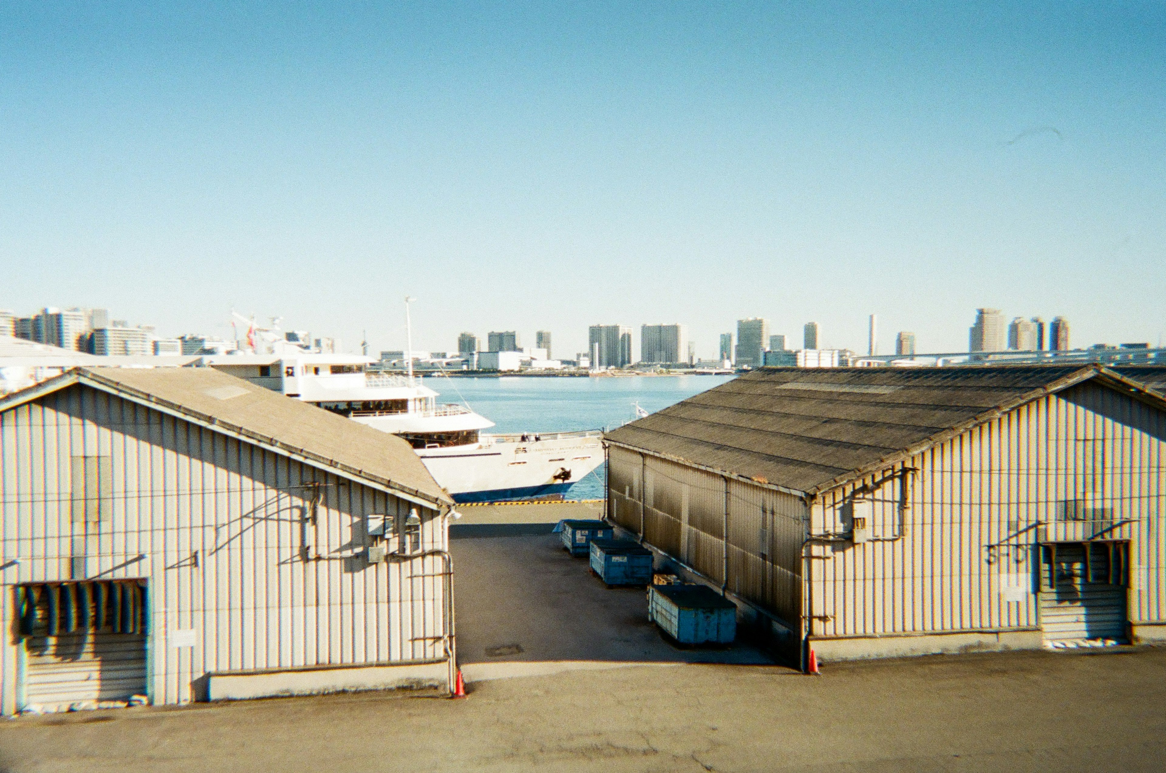 View of warehouses by the harbor with boats in the background