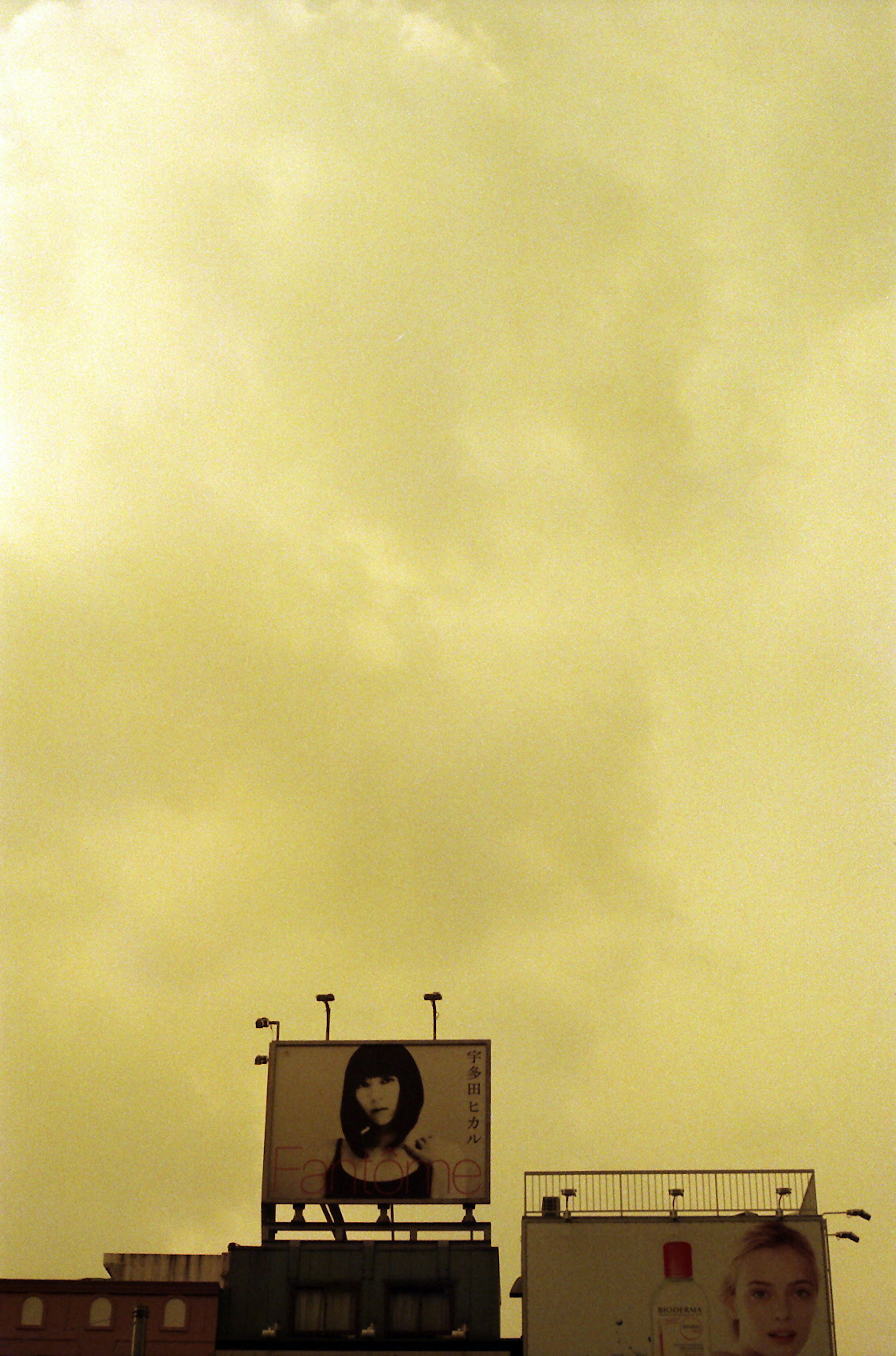 Large billboard featuring an illustrated woman's face against a yellowish sky