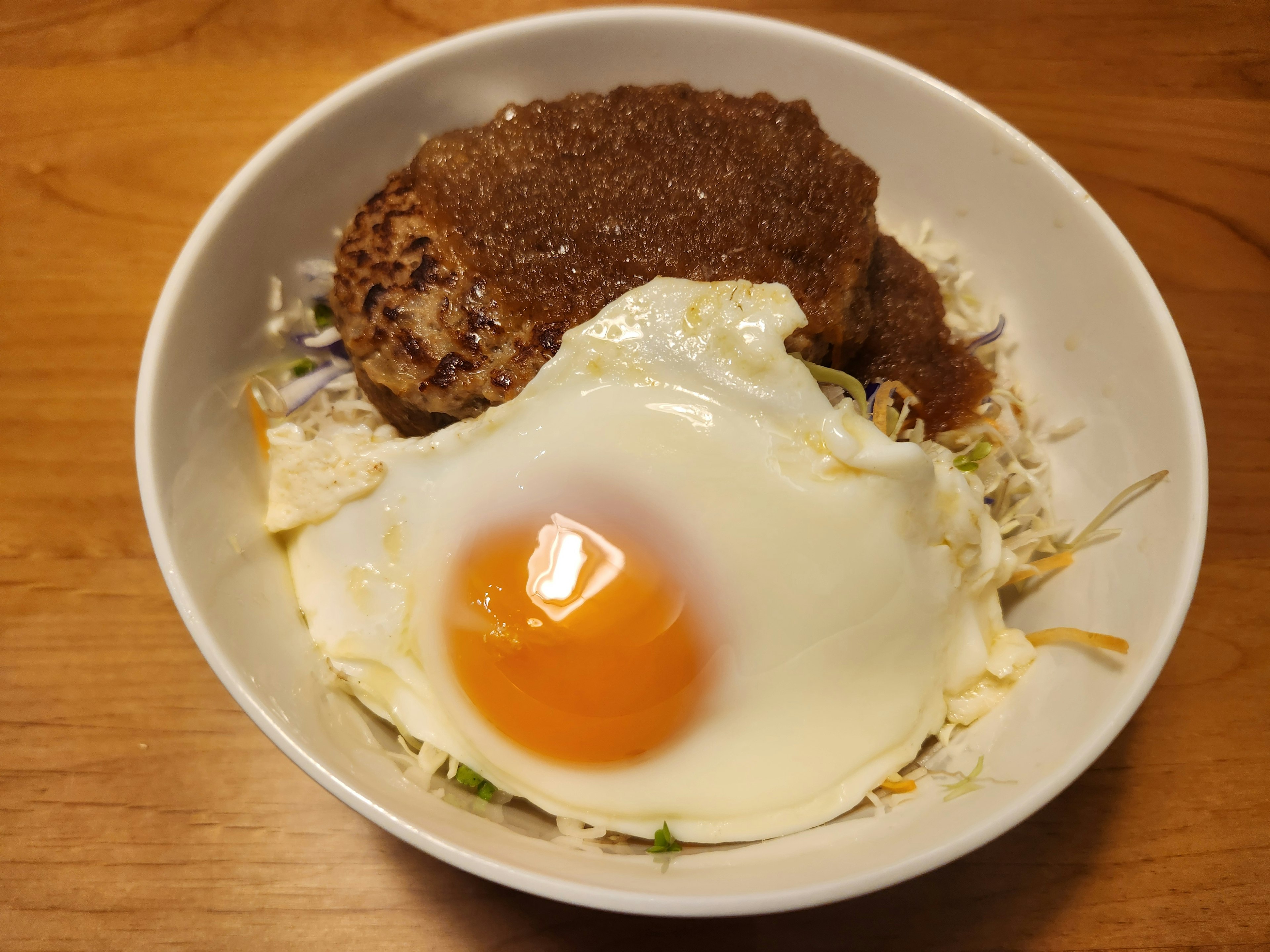 Bowl of rice topped with a fried egg and hamburger steak