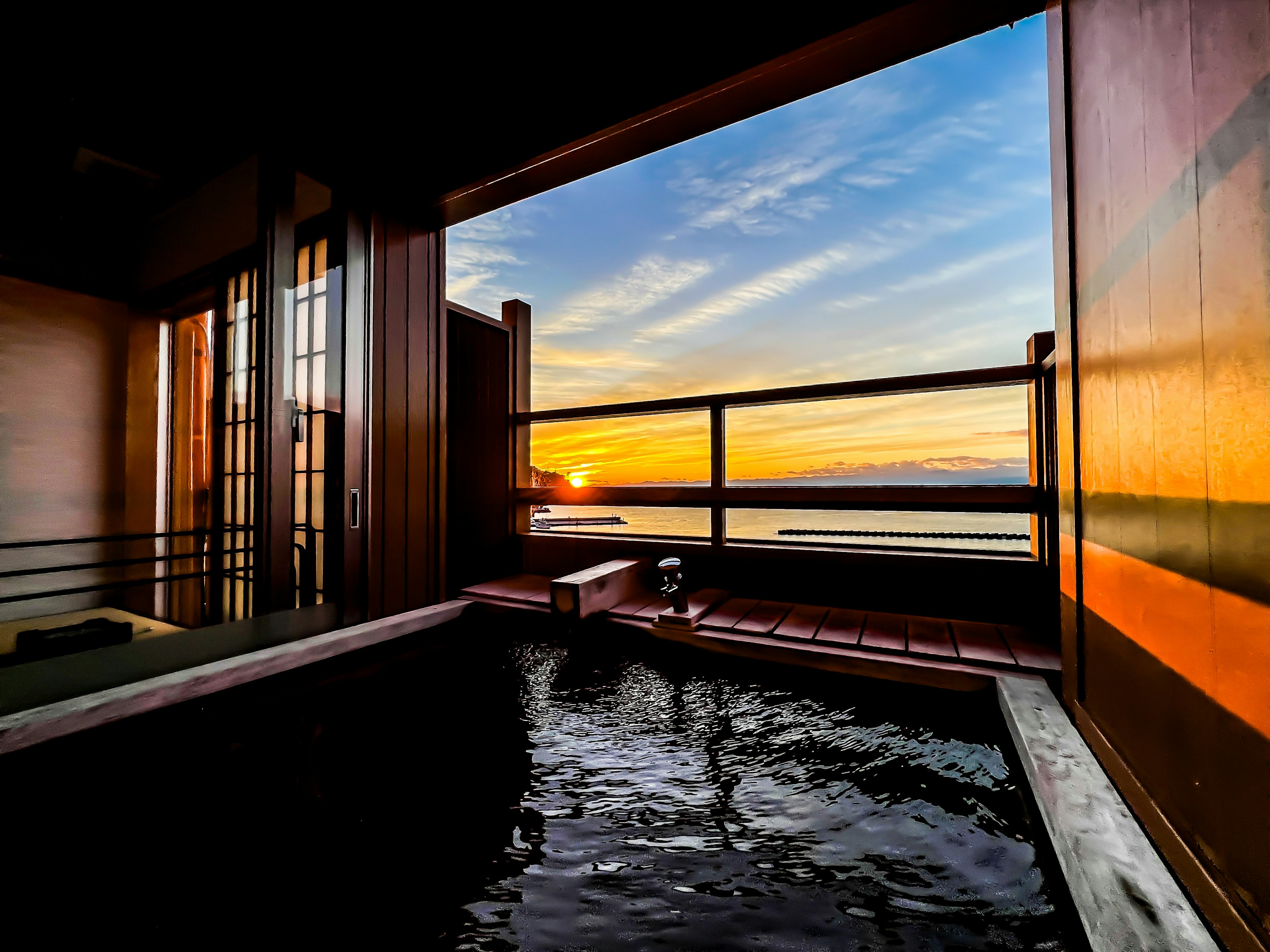 Outdoor hot spring overlooking the sea at sunset