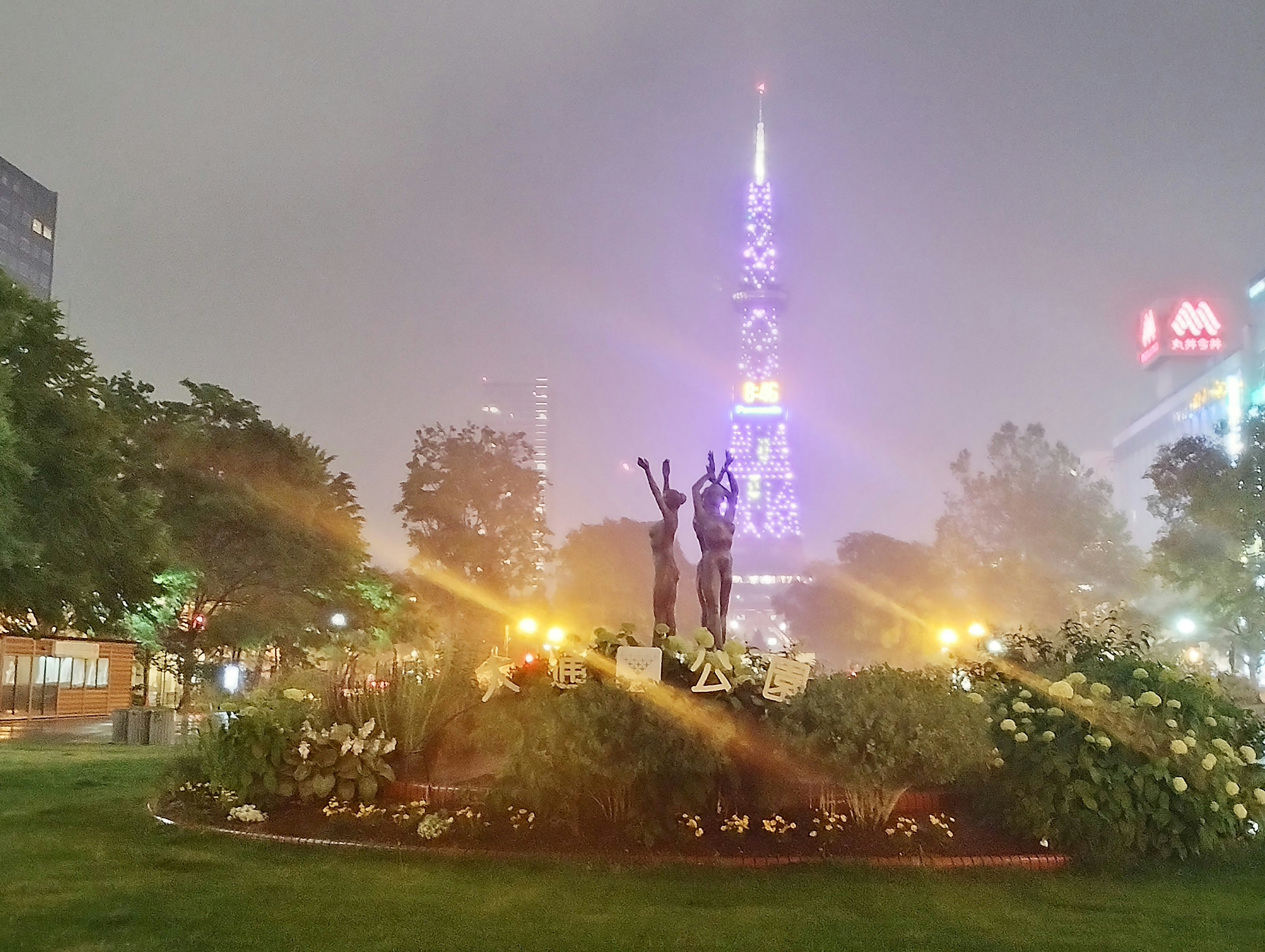 Night view of a park with a tower and sculptures