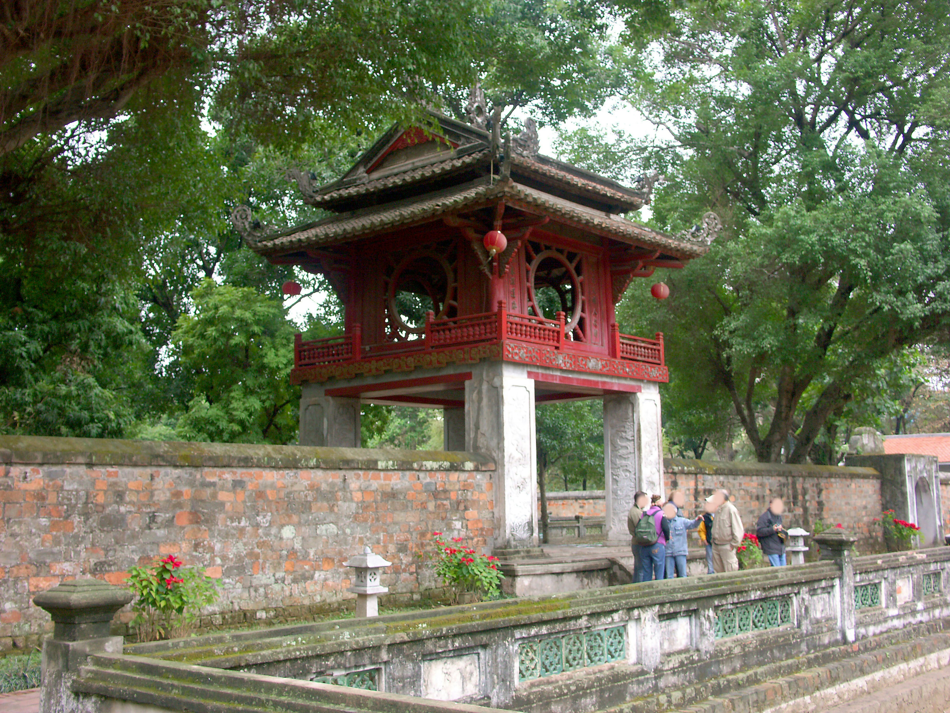 Pavillon traditionnel à toit rouge entouré de verdure luxuriante