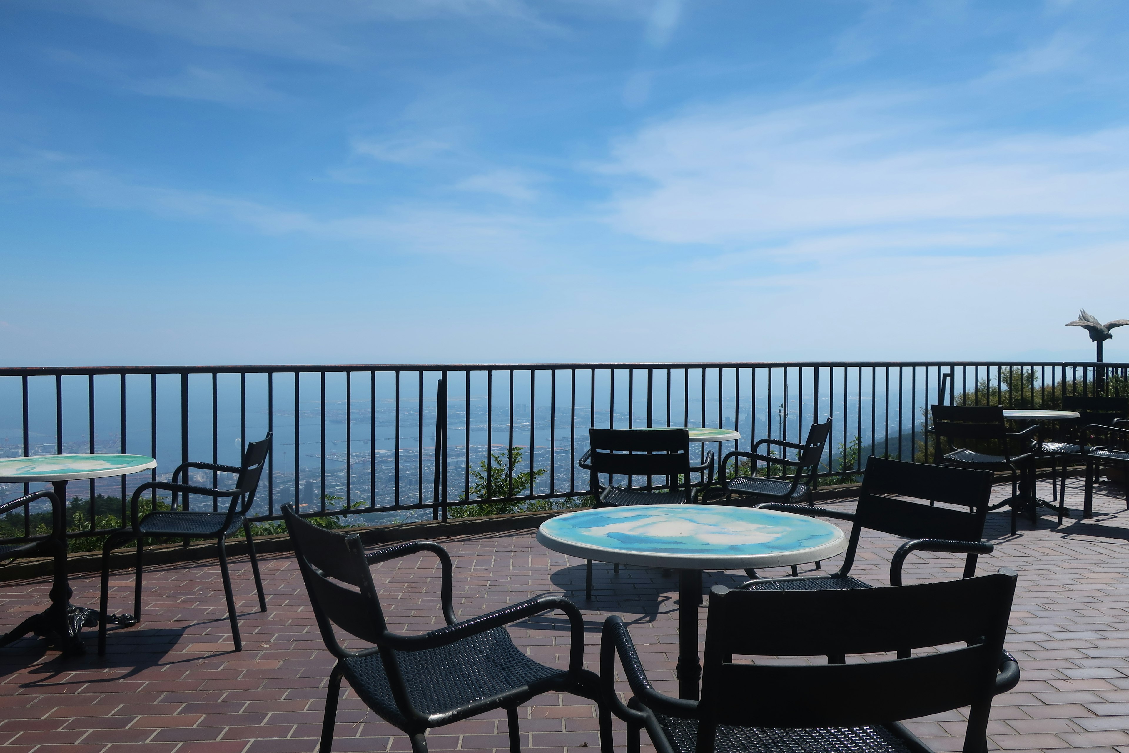 Terrace with tables and chairs overlooking blue sky and sea