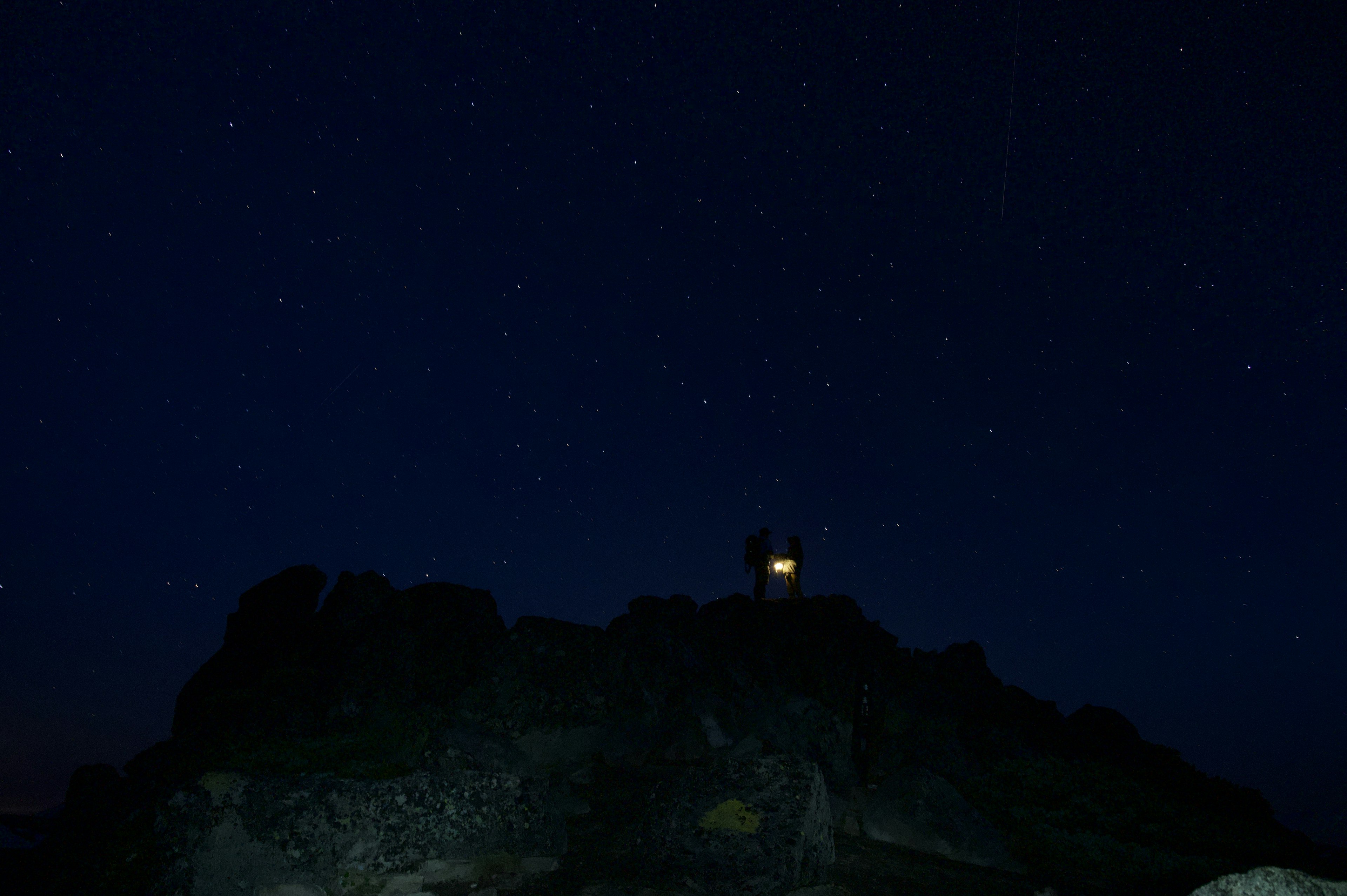 Sternenhimmel mit Licht einer Hütte auf einem Berg