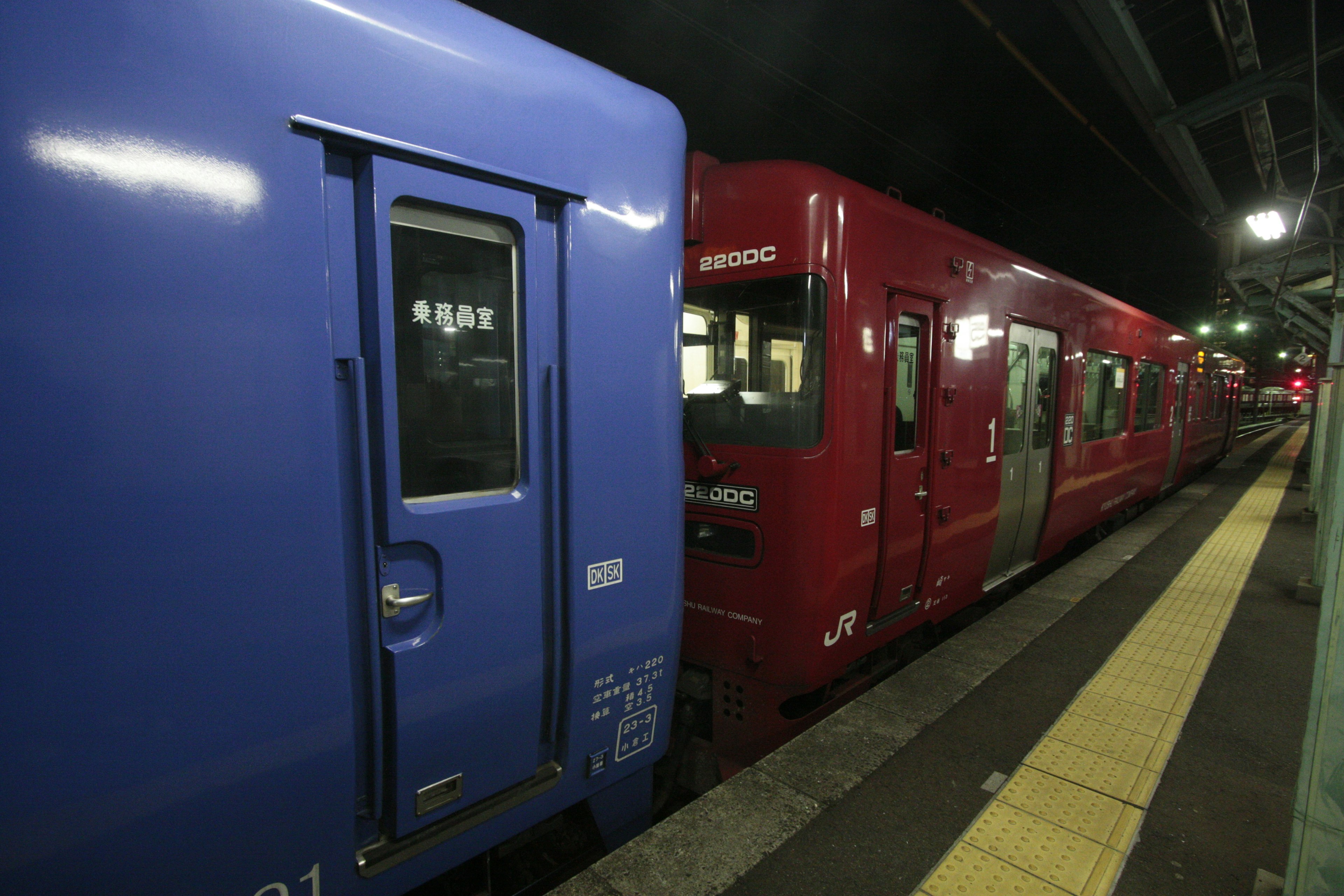 青い電車と赤い電車が夜の駅に停車している