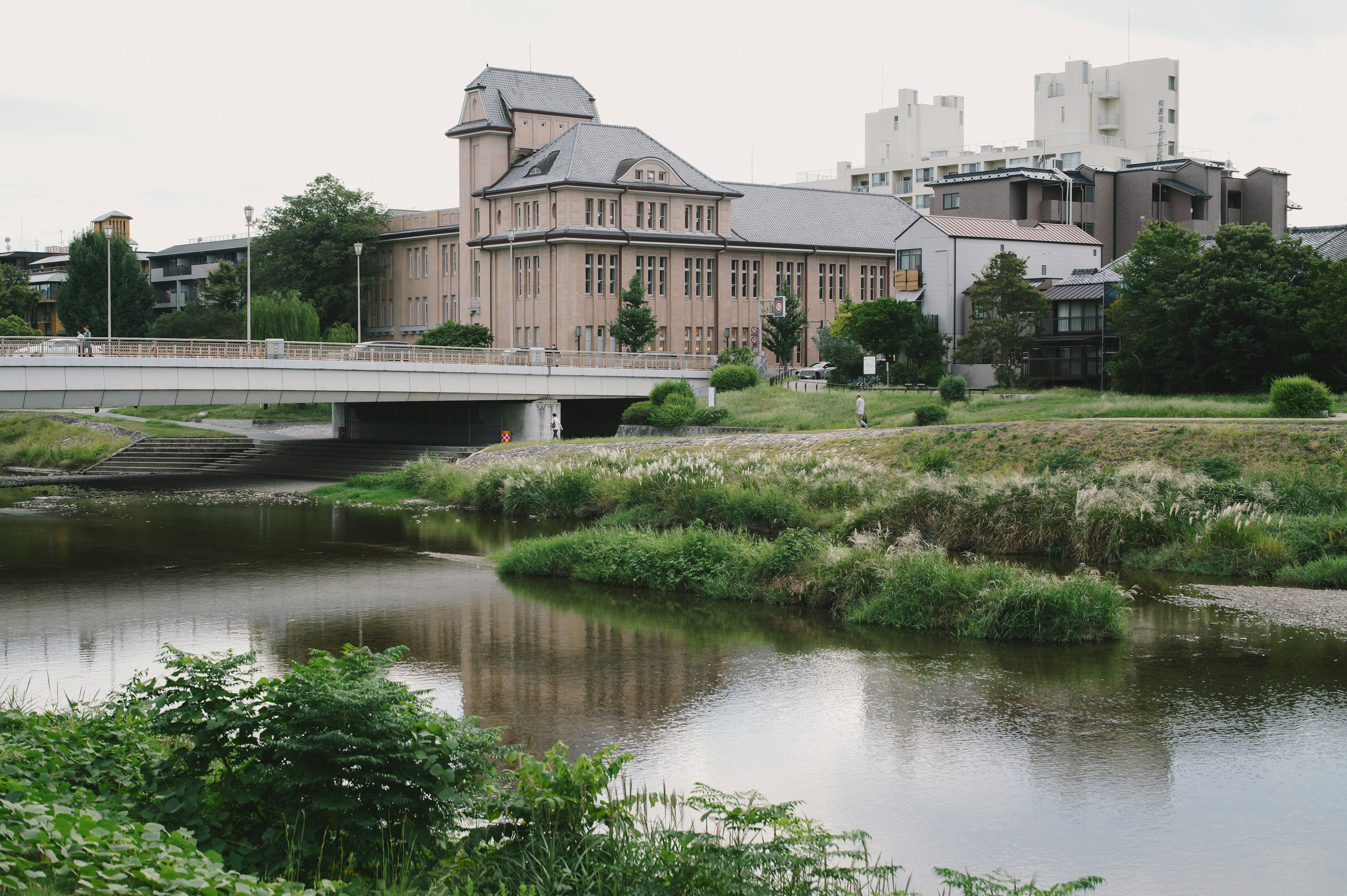 Edificio histórico junto a un río con un puente y estructuras modernas