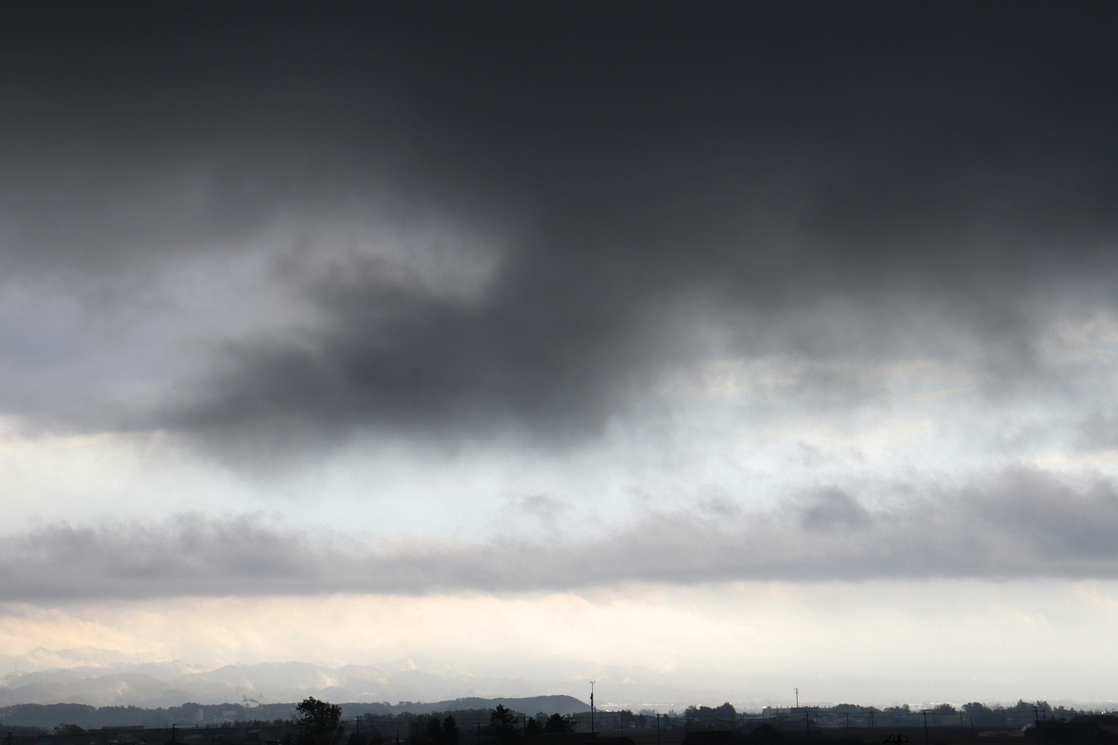 Dark clouds covering the sky with a faint horizon