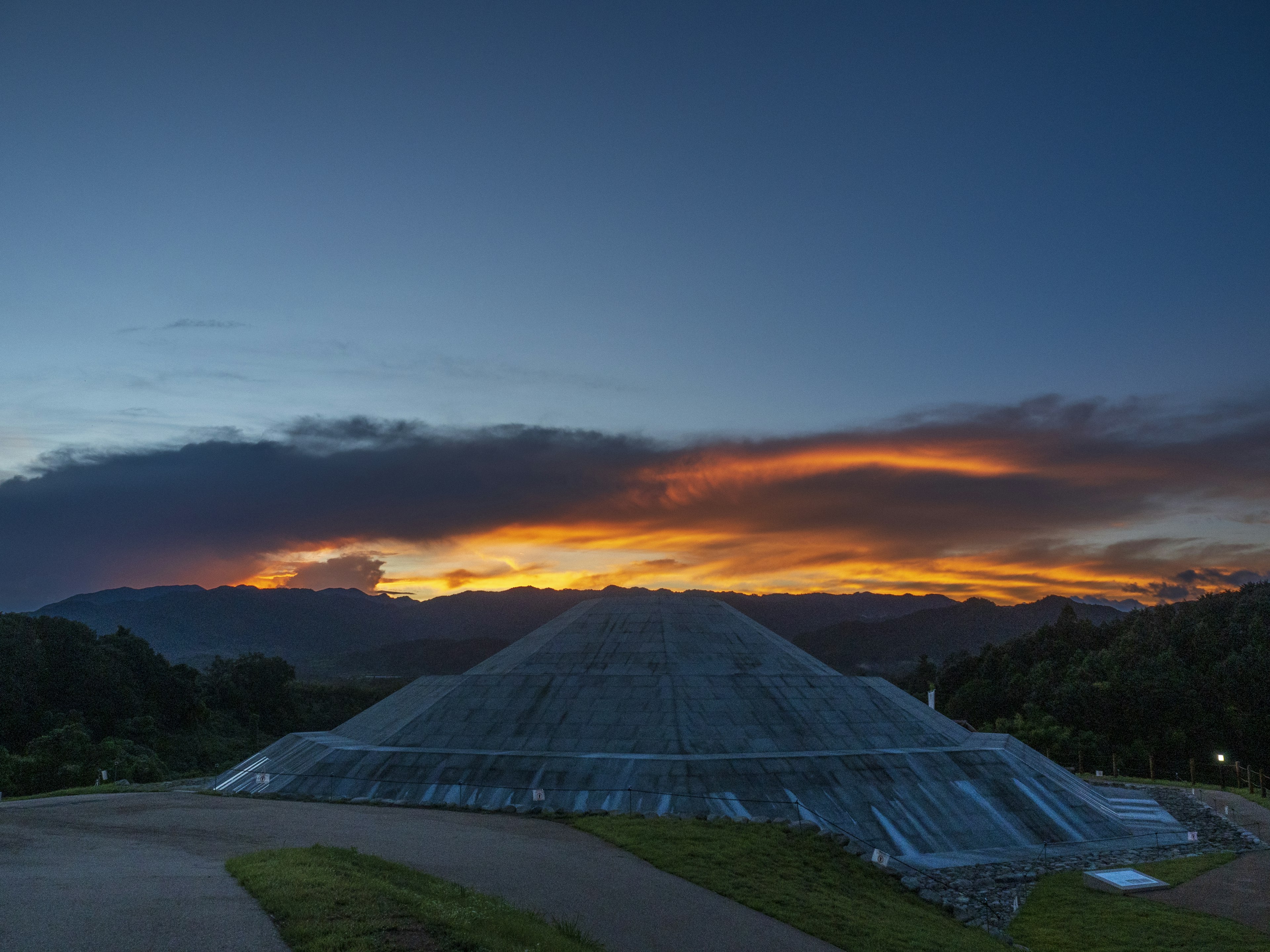 Structure en forme de pyramide sous un coucher de soleil avec des nuages dramatiques